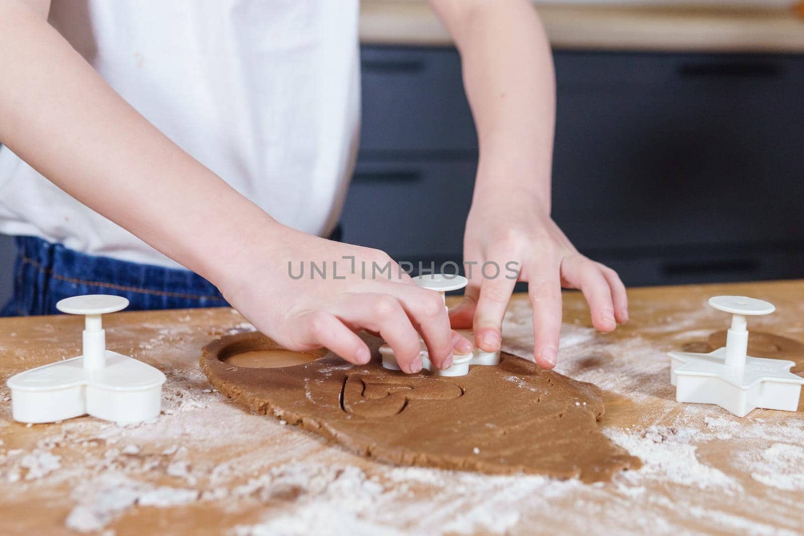 A little girl makes heart-shaped cookies from rye dough. The concept of Valentine's Day and healthy baking. Cooking cookies in close-up.