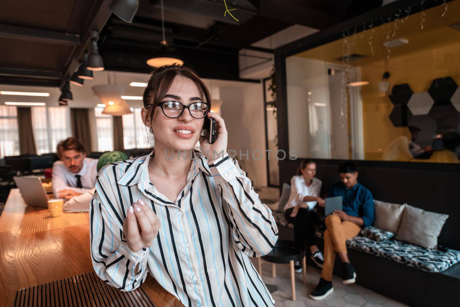 Businesswoman with glasses using mobile phone at modern startup open plan office interior. Selective focus by dotshock