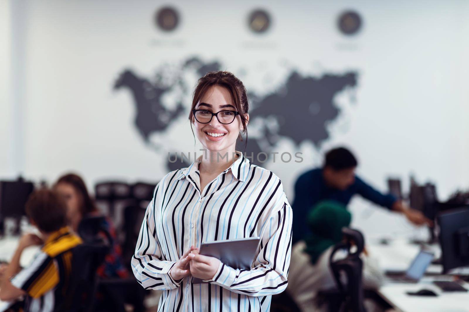 Portrait of businesswoman in casual clothes holding tablet computer at modern startup open plan office interior. Selective focus by dotshock