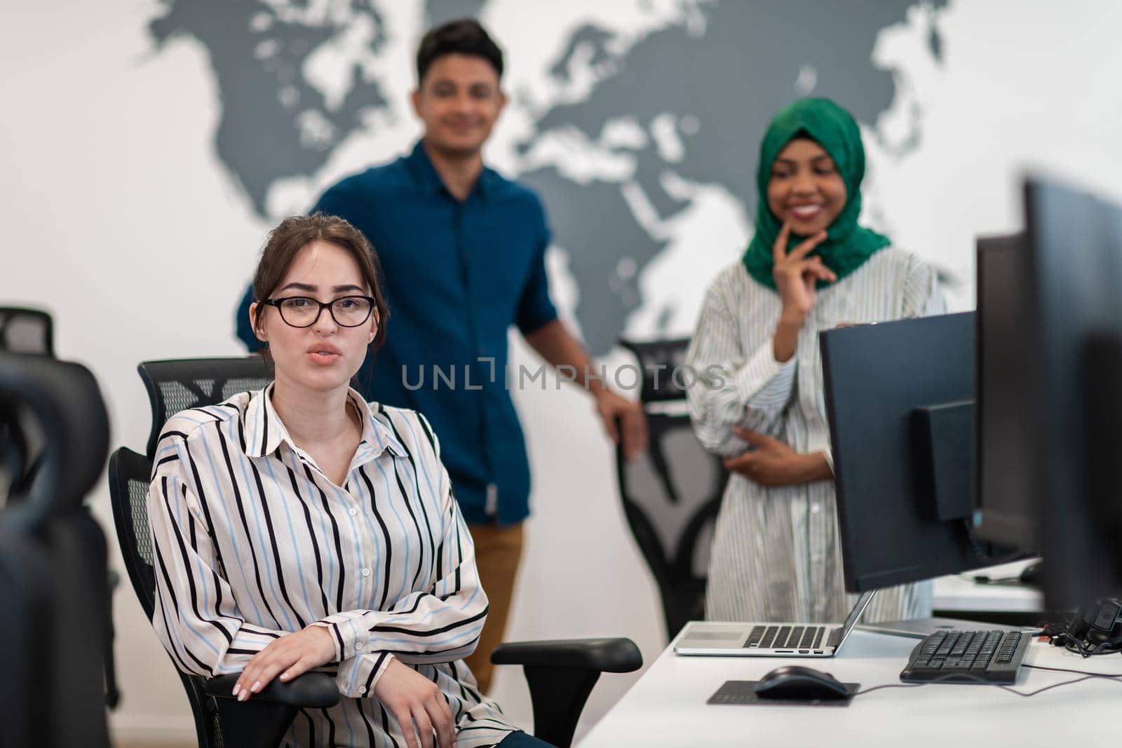 Multiethnic startup business team Arabian woman wearing a hijab on meeting in modern open plan office interior brainstorming, working on laptop and desktop computer. Selective focus by dotshock