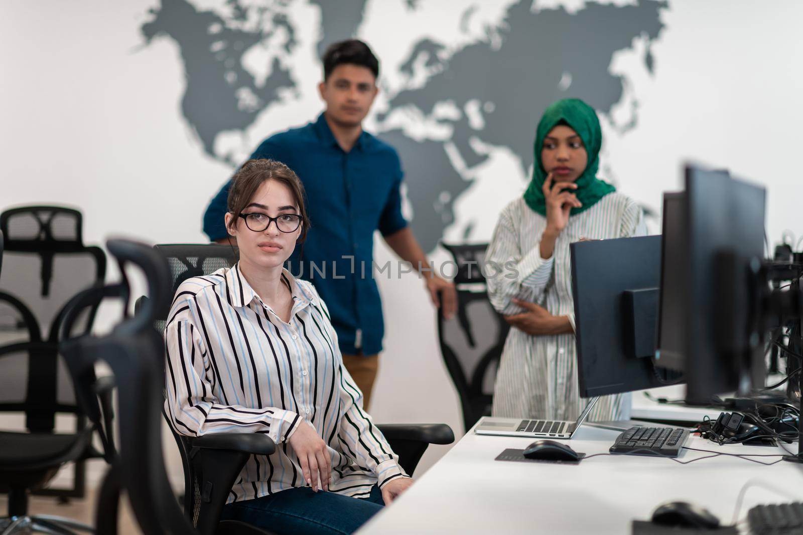 Multiethnic startup business team Arabian woman wearing a hijab on meeting in modern open plan office interior brainstorming, working on laptop and desktop computer. Selective focus by dotshock