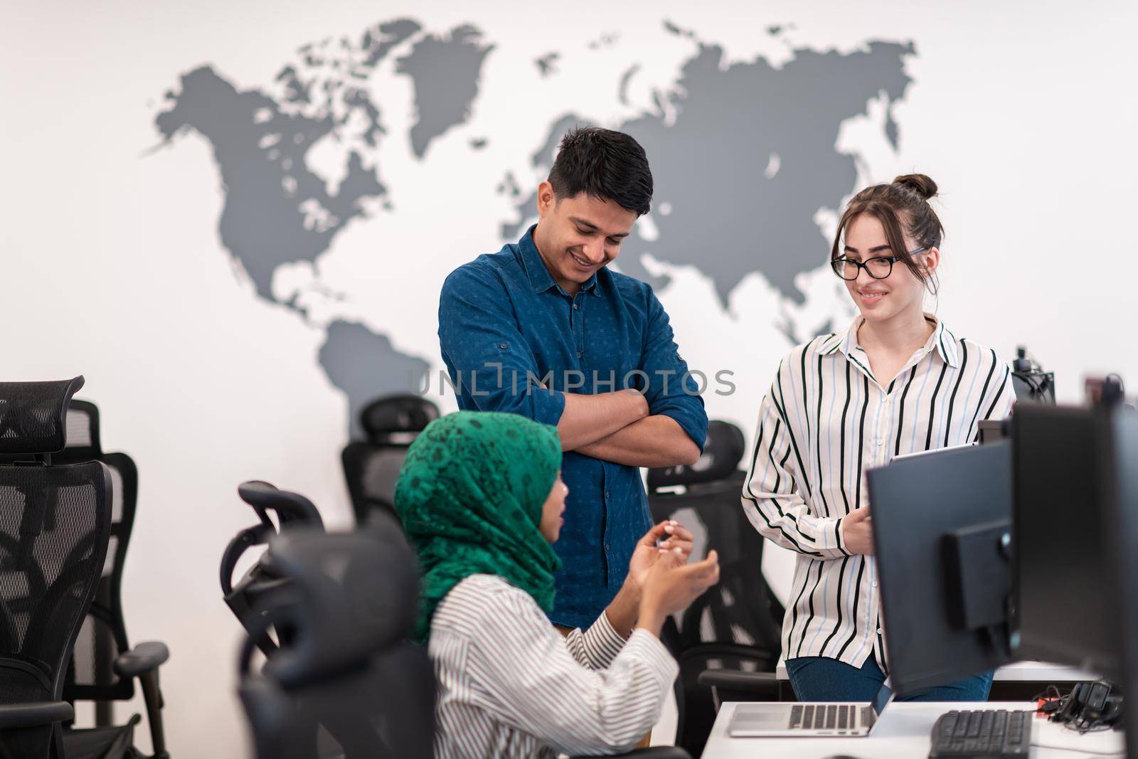 Multiethnic startup business team Arabian woman wearing a hijab on meeting in modern open plan office interior brainstorming, working on laptop and desktop computer. Selective focus. High-quality photo