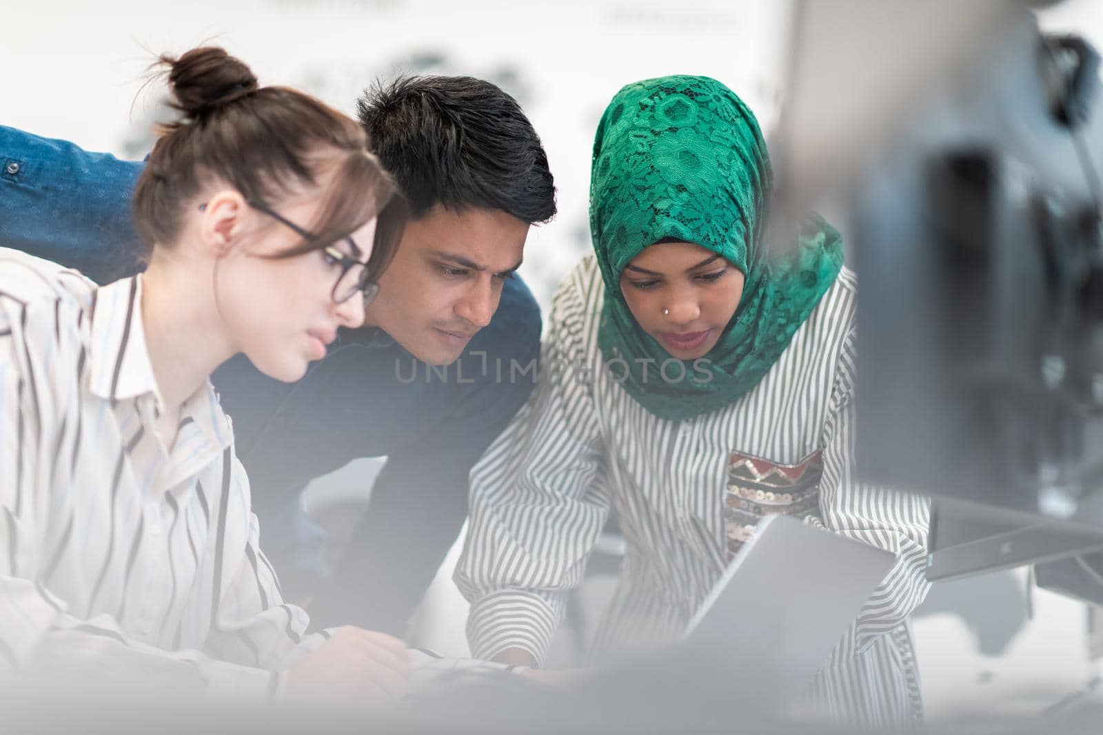 Multiethnic startup business team Arabian woman wearing a hijab on meeting in modern open plan office interior brainstorming, working on laptop and desktop computer. Selective focus. High-quality photo