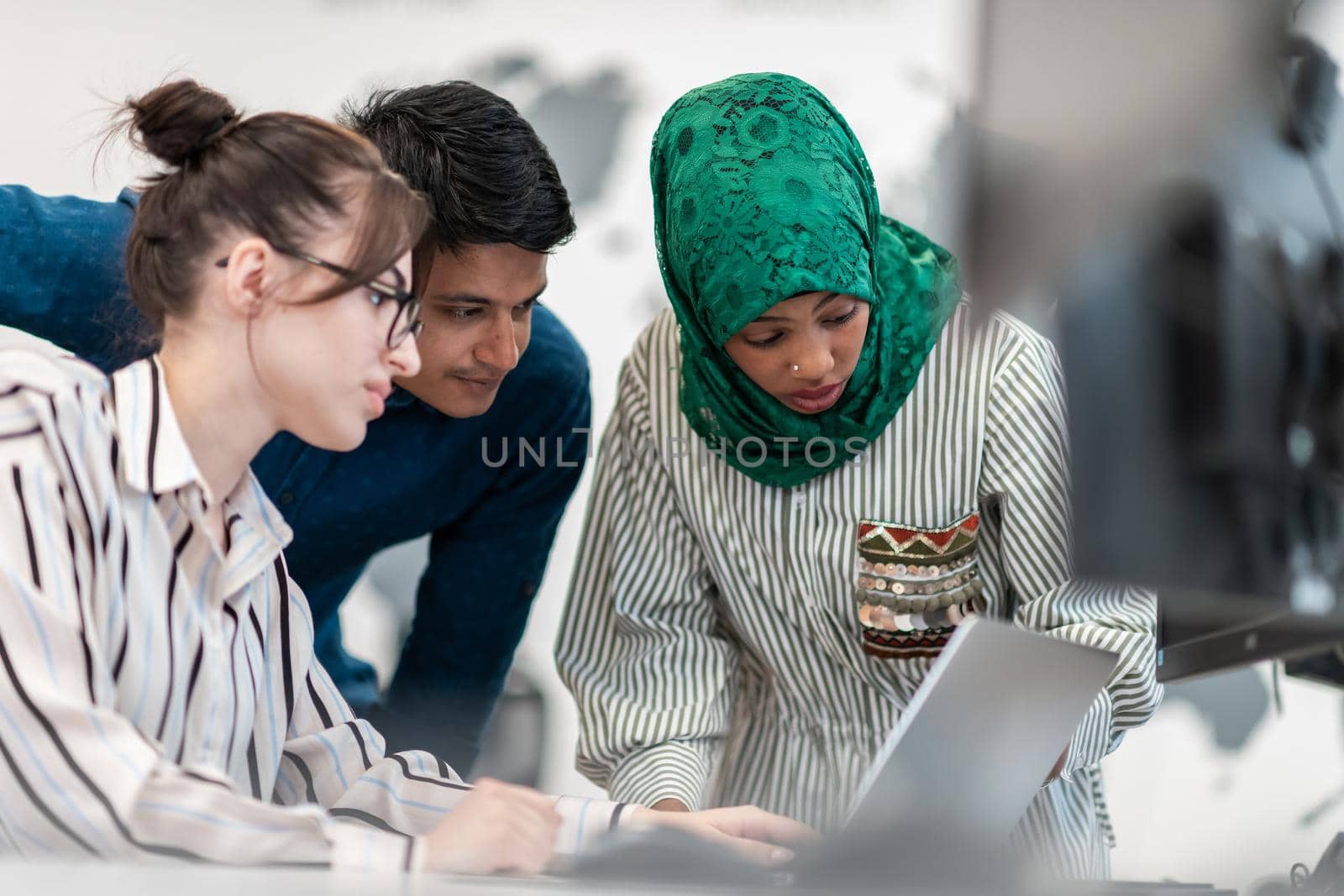 Multiethnic startup business team Arabian woman wearing a hijab on meeting in modern open plan office interior brainstorming, working on laptop and desktop computer. Selective focus by dotshock