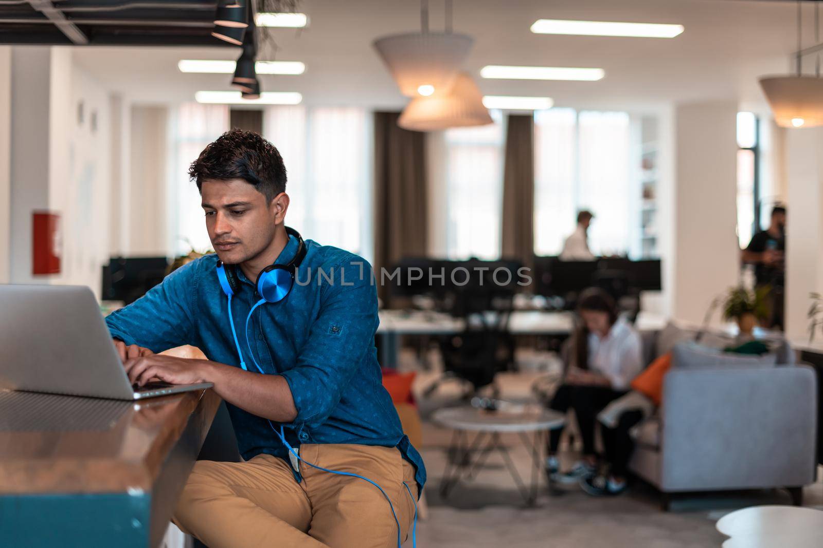 Casual business man with headphones around his using laptop for online meeting. Selective focus by dotshock