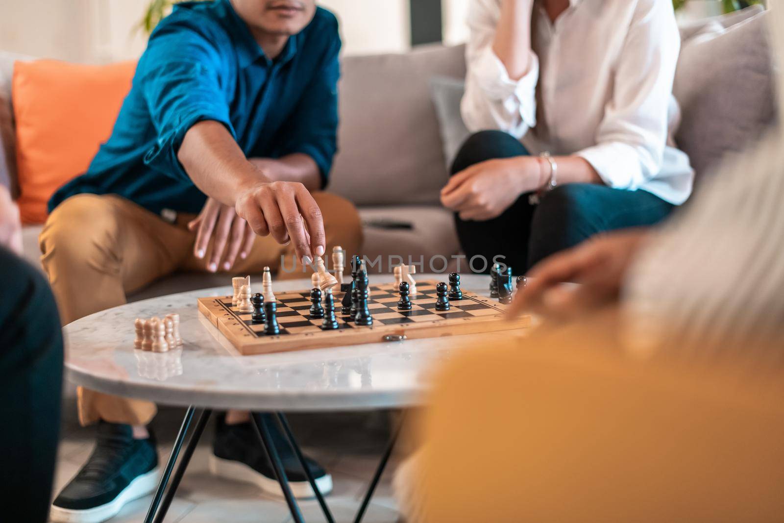 Multiethnic group of businesspeople playing chess while having a break in relaxation area at modern startup office. Selective focus. High-quality photo