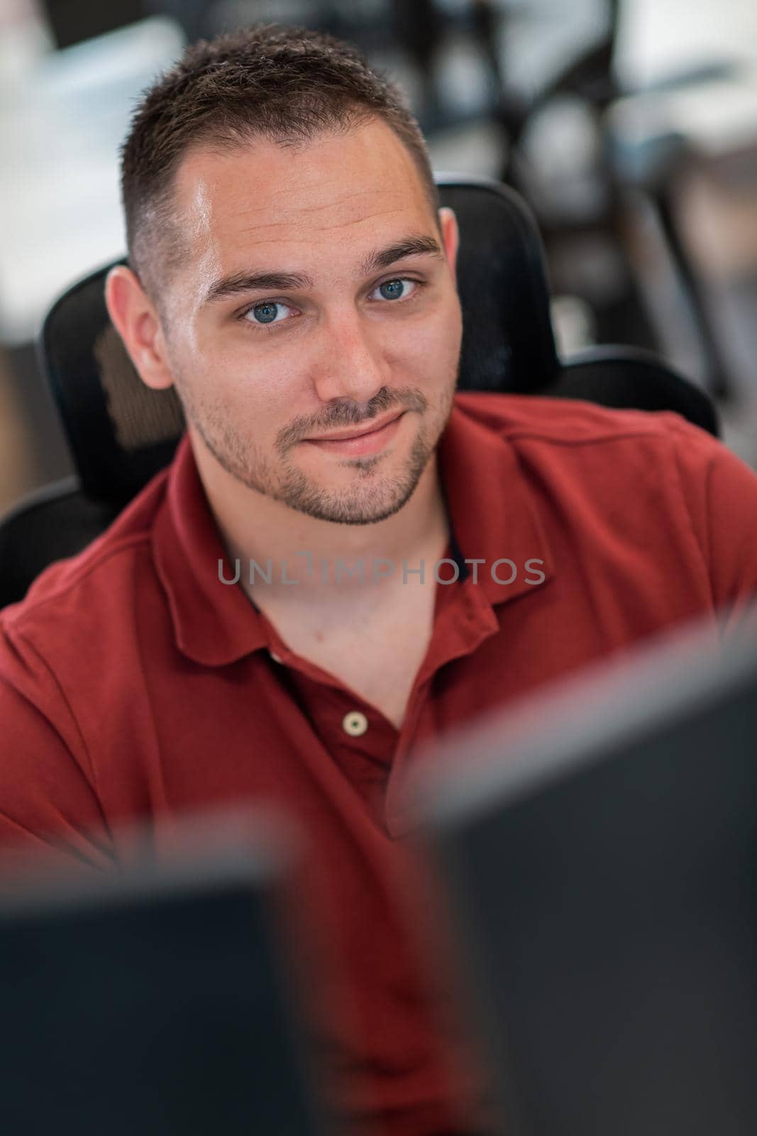 Casual businessman working on a desktop computer in modern open plan startup office interior. Selective focus. High-quality photo