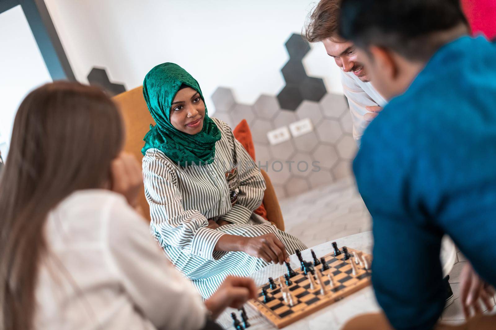 Multiethnic group of businesspeople playing chess while having a break in relaxation area at modern startup office. Selective focus. High-quality photo