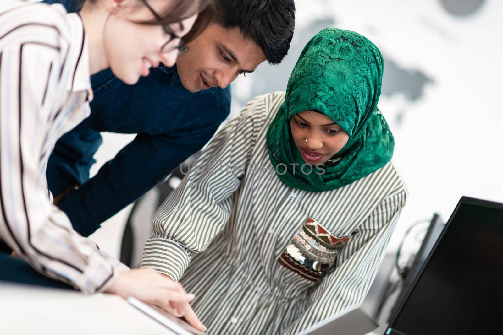 Multiethnic startup business team Arabian woman wearing a hijab on meeting in modern open plan office interior brainstorming, working on laptop and desktop computer. Selective focus by dotshock