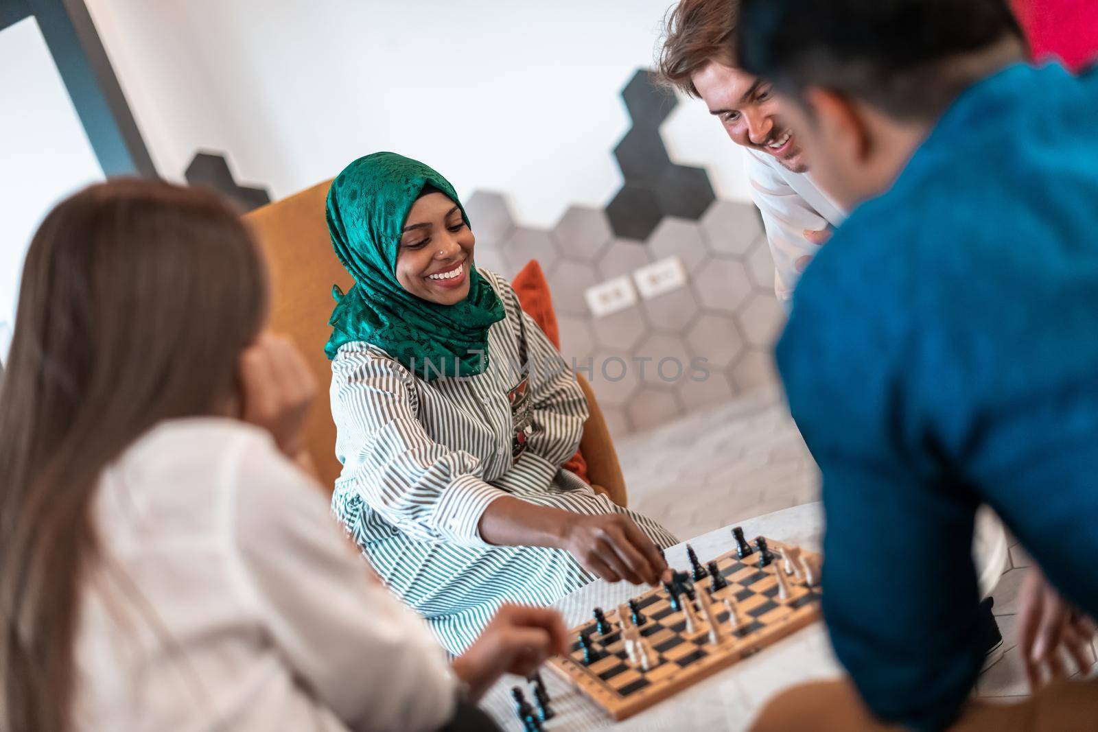 Multiethnic group of businesspeople playing chess while having a break in relaxation area at modern startup office. Selective focus. High-quality photo