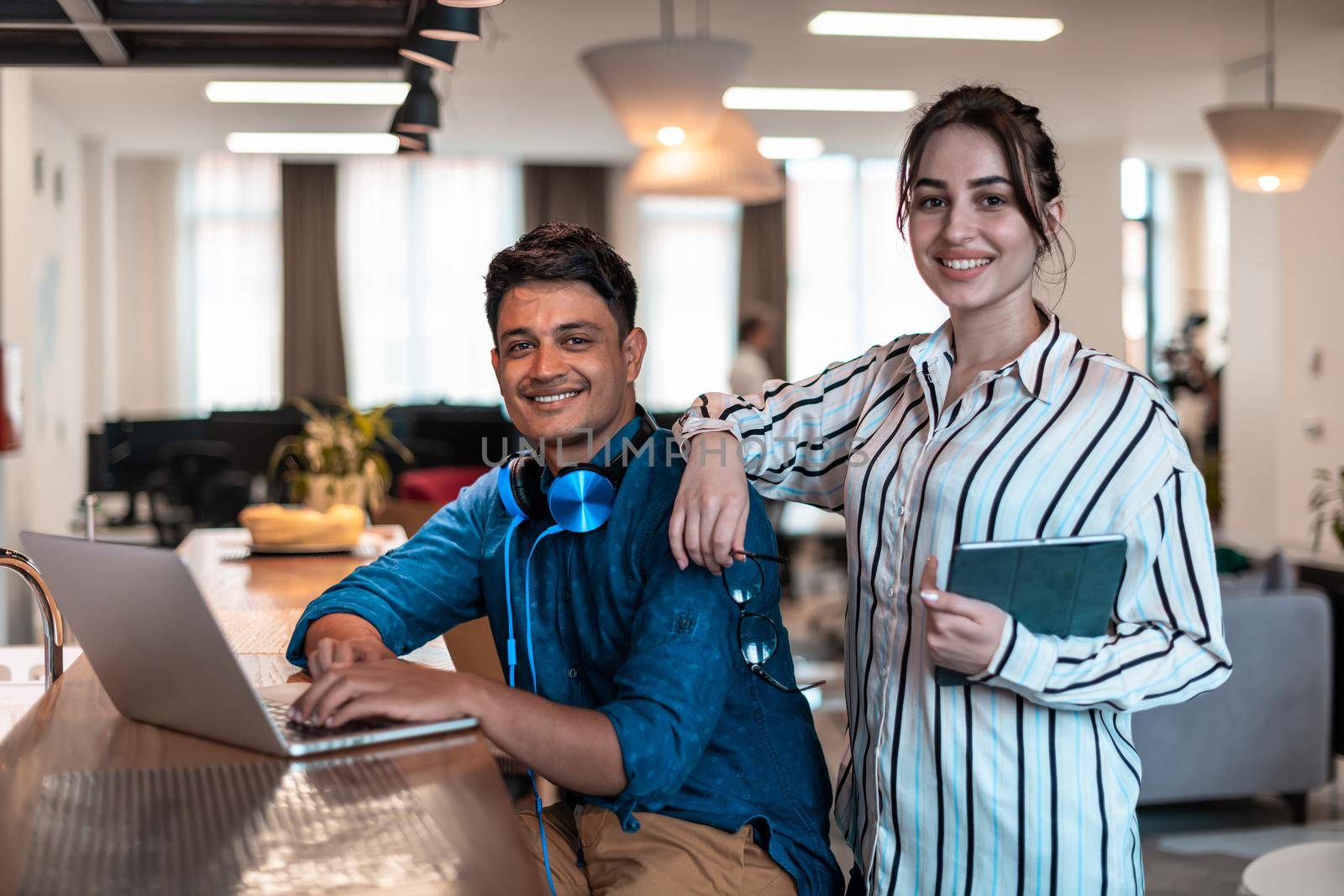 Multiethnic business people man with a female colleague working together on tablet and laptop computer in relaxation area of modern startup office by dotshock