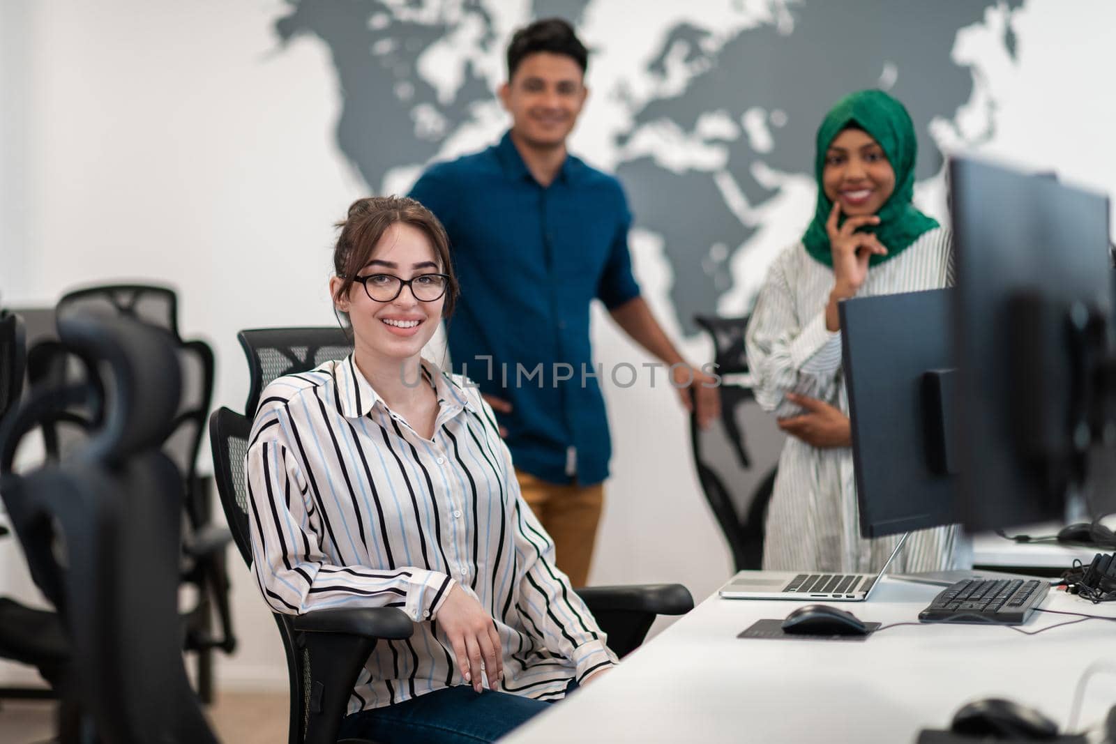 Multiethnic startup business team Arabian woman wearing a hijab on meeting in modern open plan office interior brainstorming, working on laptop and desktop computer. Selective focus. High-quality photo