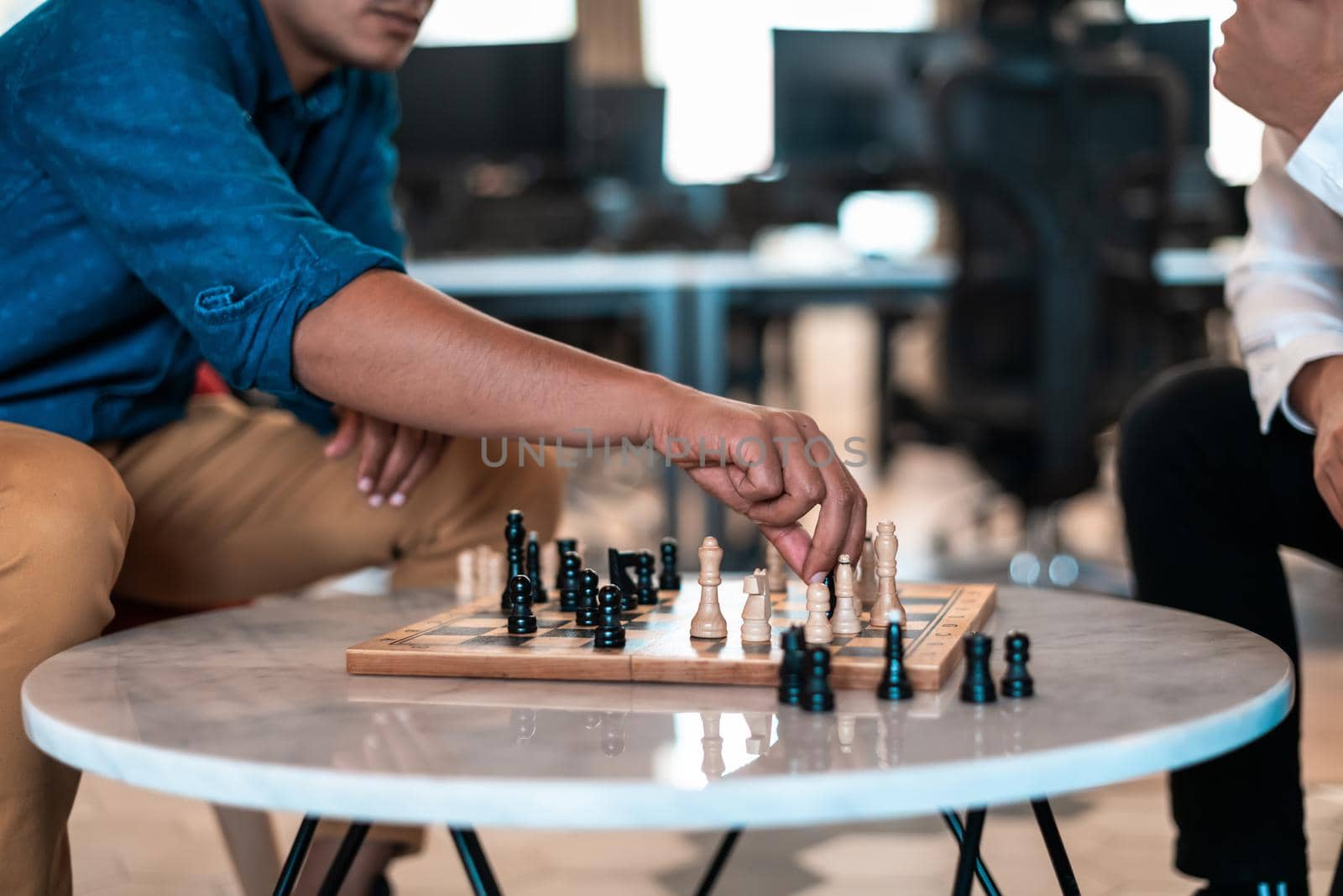 Multiethnic group of businesspeople playing chess while having a break in relaxation area at modern startup office. High-quality photo