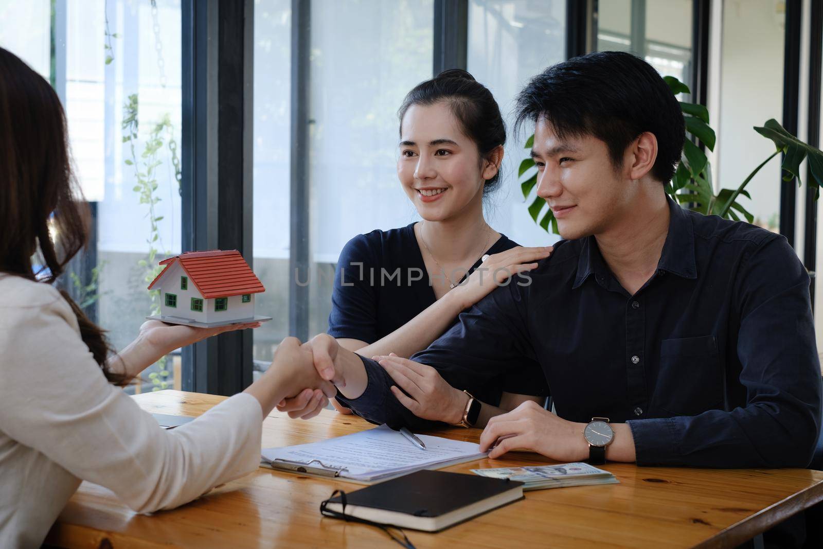 Business woman and young couple shake hand after signing agreement for buying house. Bank manager and real estate concept
