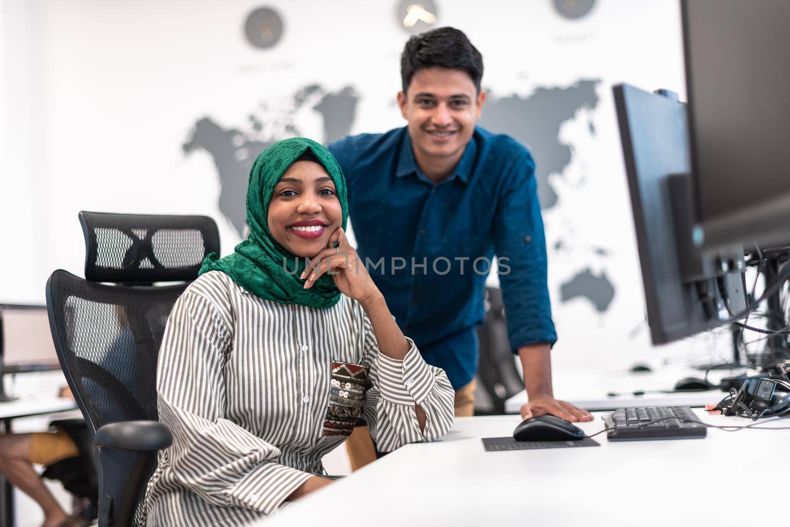 Multiethnic startup business team Arabian woman wearing a hijab on meeting in modern open plan office interior brainstorming, working on laptop and desktop computer. Selective focus. High-quality photo