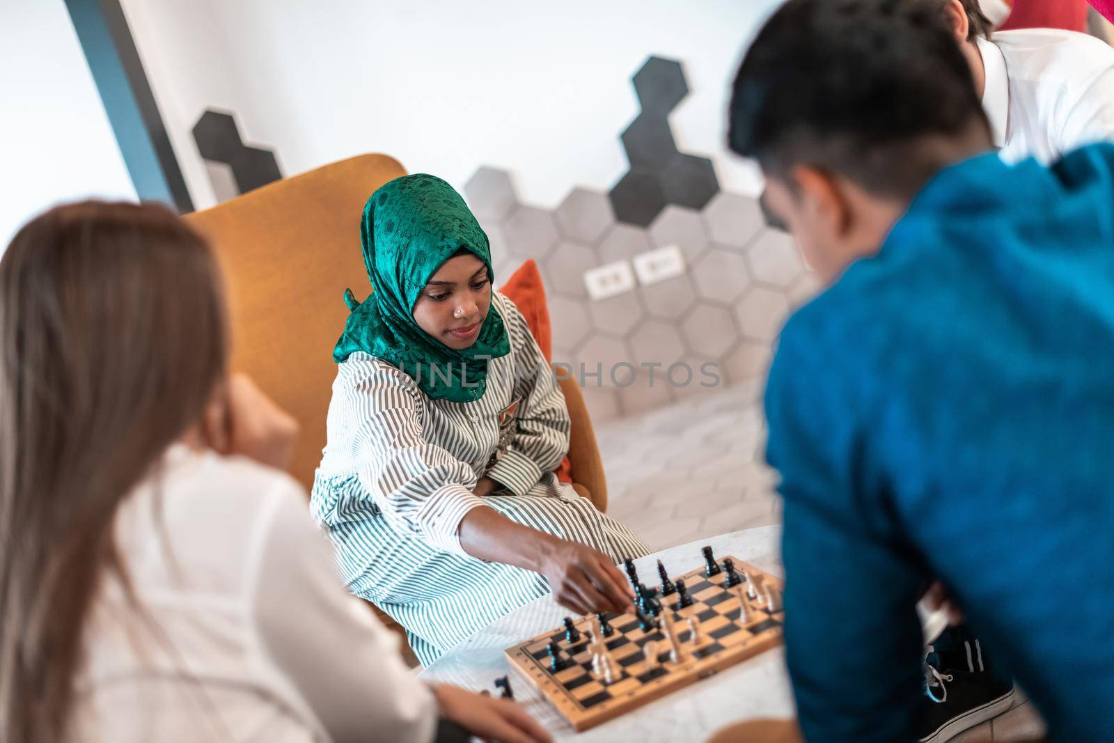 Multiethnic group of businesspeople playing chess while having a break in relaxation area at modern startup office. High-quality photo