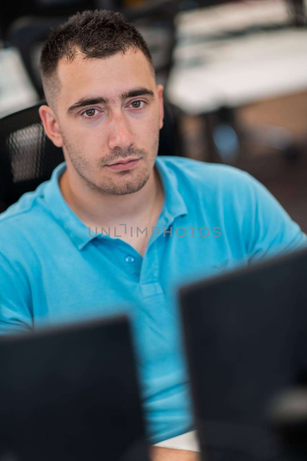 Casual business man working on desktop computer in modern open plan startup office interior. Selective focus by dotshock