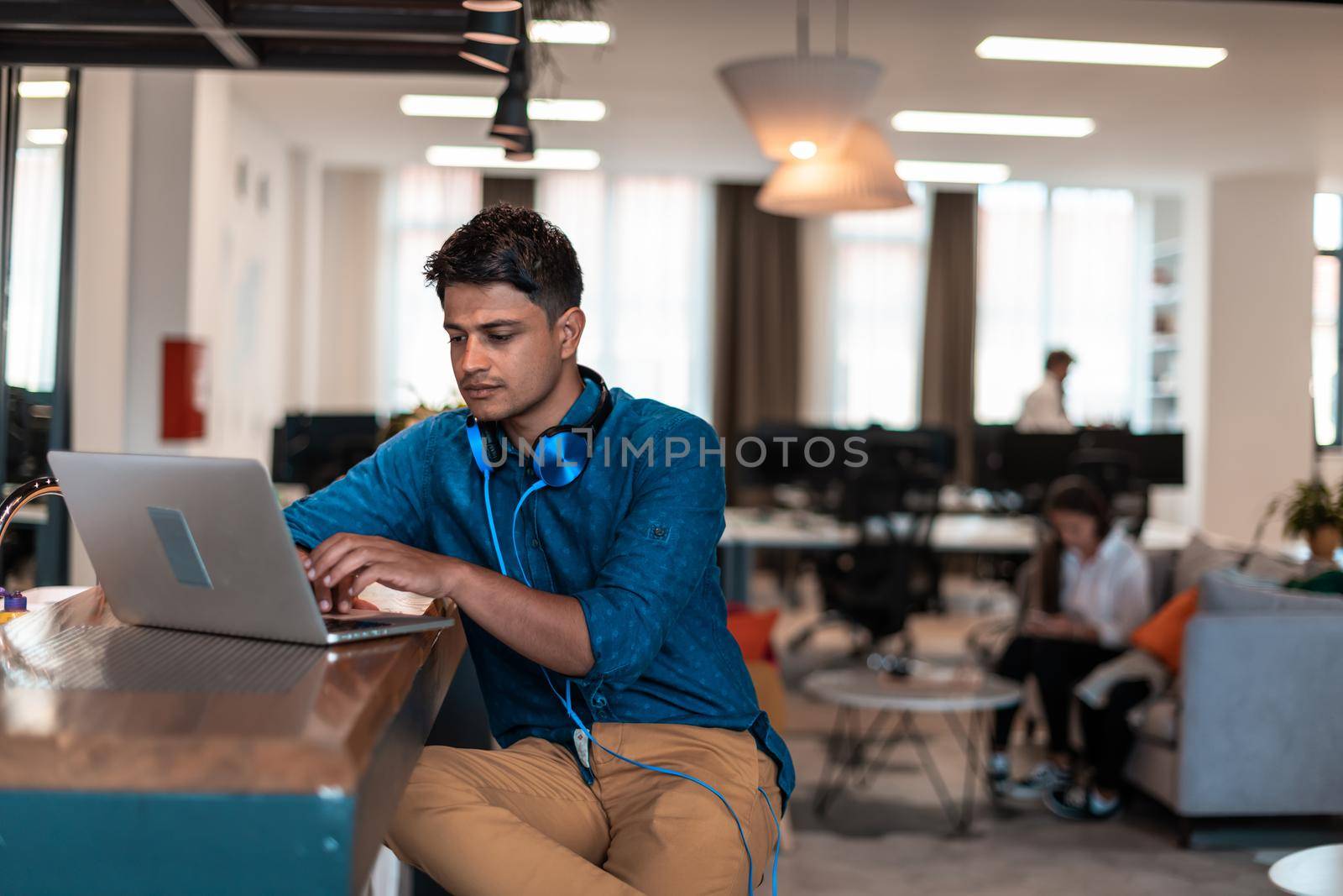 Casual business man with headphones around his using laptop for online meeting. Selective focus by dotshock