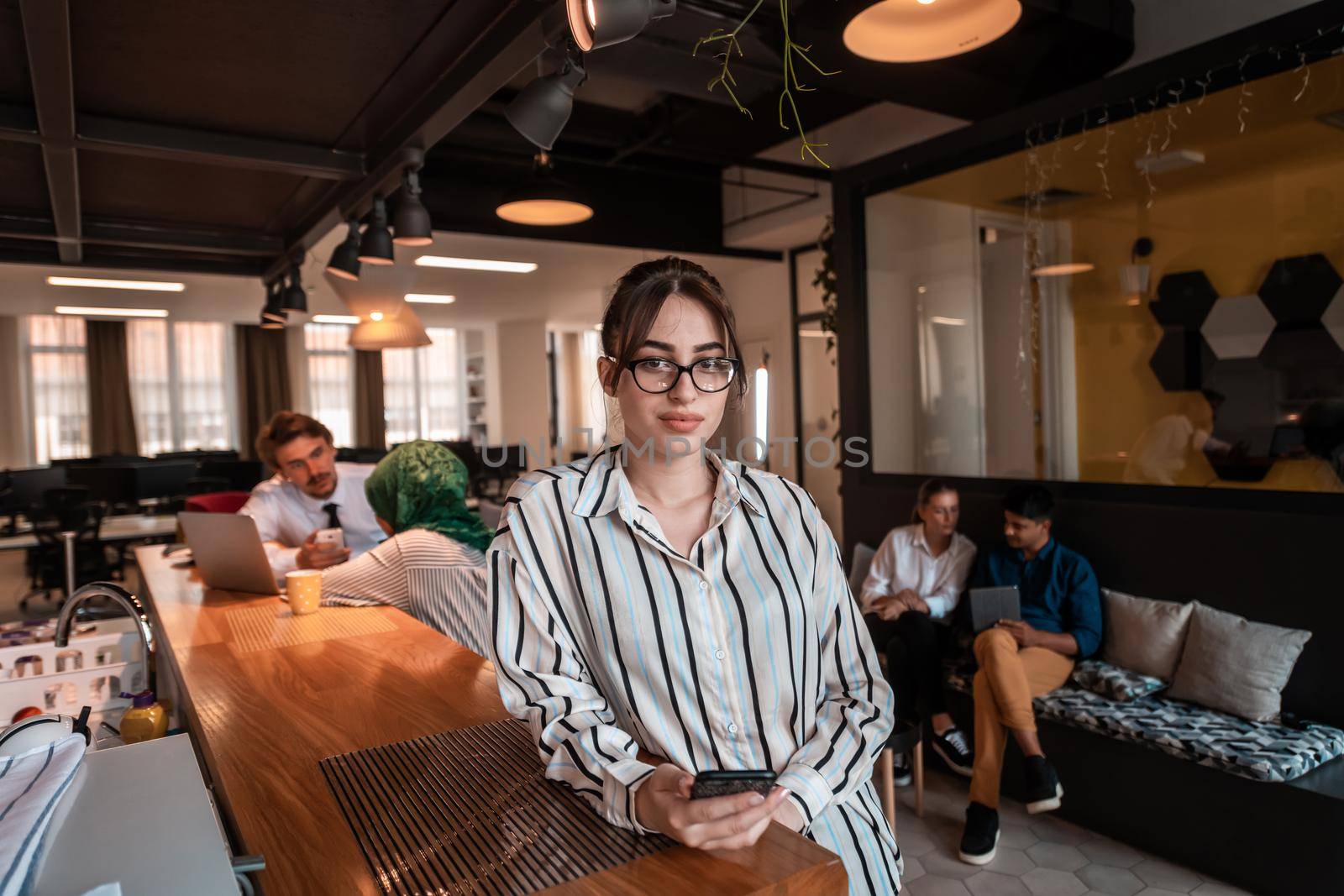 Businesswoman with glasses using mobile phone at modern startup open plan office interior. Selective focus by dotshock