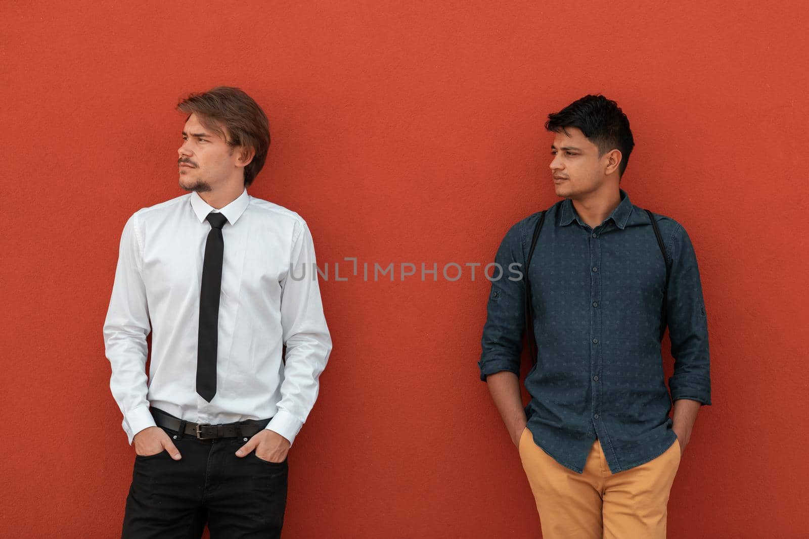 Casual multiethnic startup businessmen during a break from work in front of the red wall outside. High-quality photo