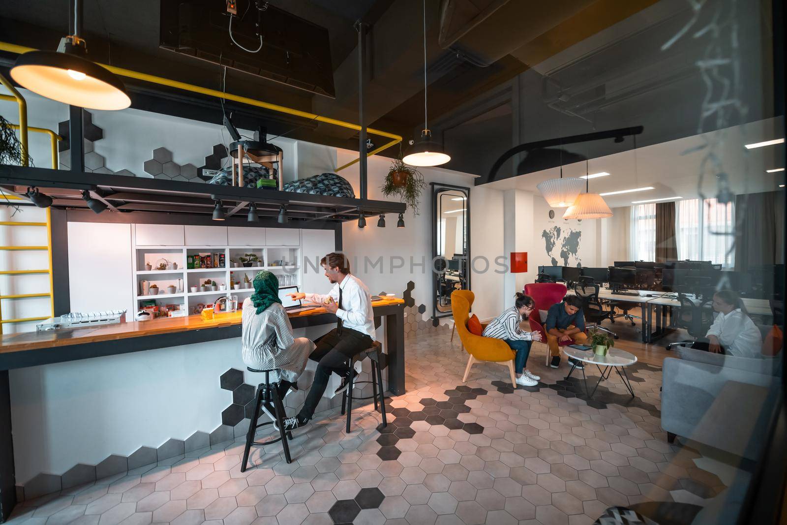 Group of casual multiethnic business people taking break from the work doing different things while enjoying free time in relaxation area at modern open plan startup office by dotshock