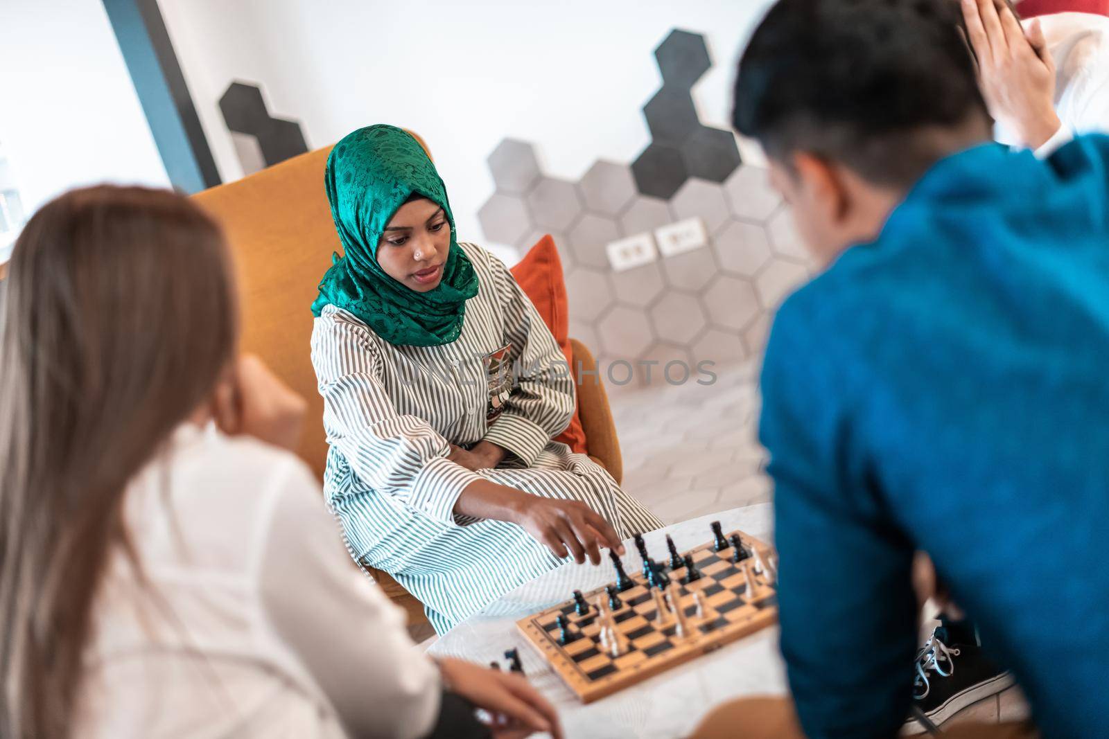 Multiethnic group of businesspeople playing chess while having a break in relaxation area at modern startup office. High-quality photo