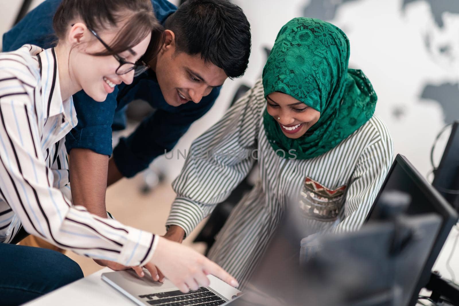 Multiethnic startup business team Arabian woman wearing a hijab on meeting in modern open plan office interior brainstorming, working on laptop and desktop computer. Selective focus. High-quality photo