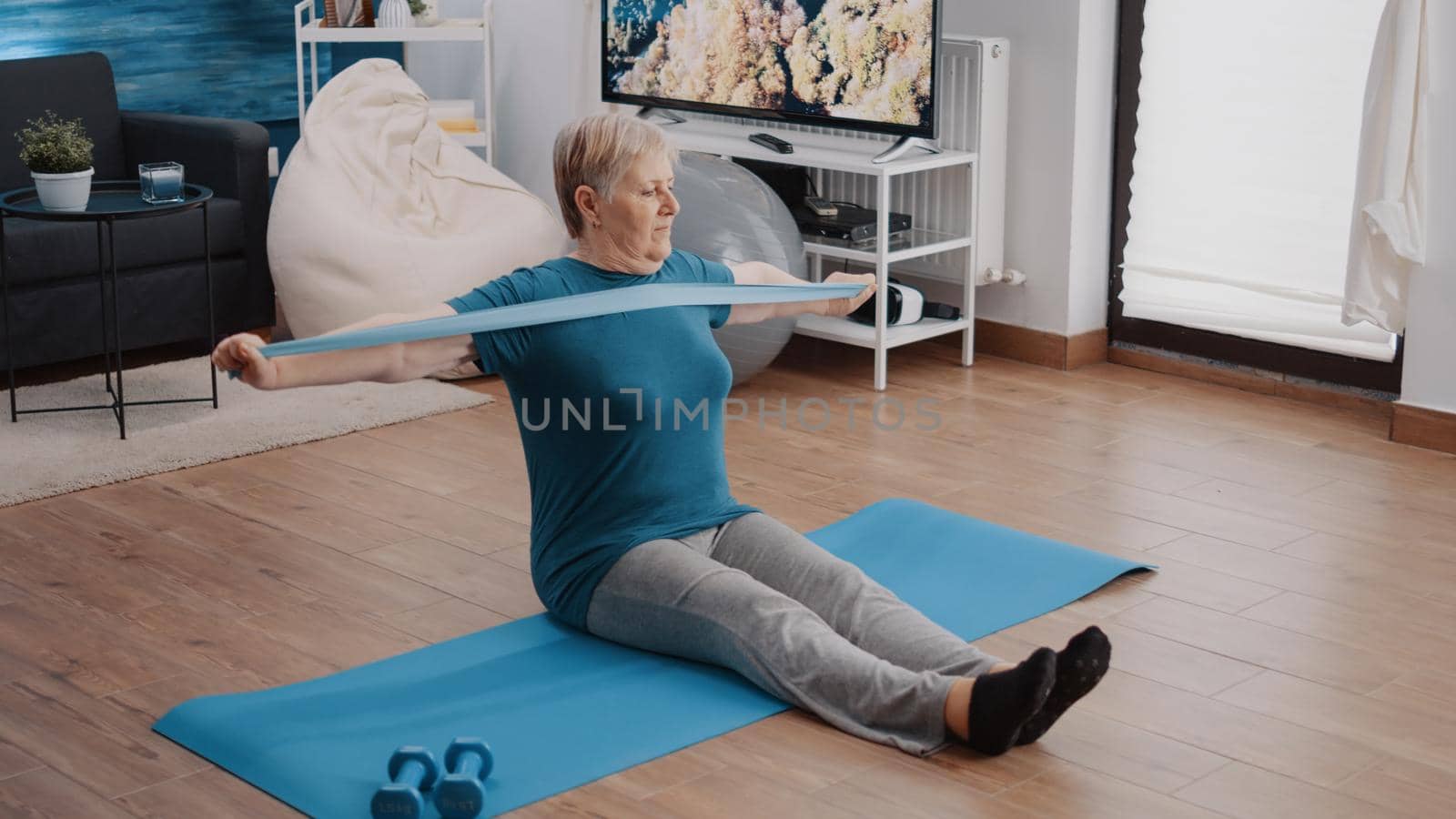 Retired adult using resistance band to stretch arms muscles by DCStudio