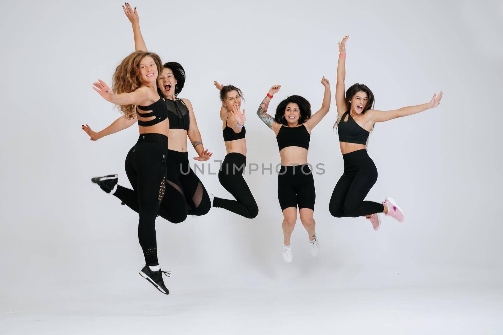 diverse models jump up, enjoying time together, look at camera having smile and natural unique beauty