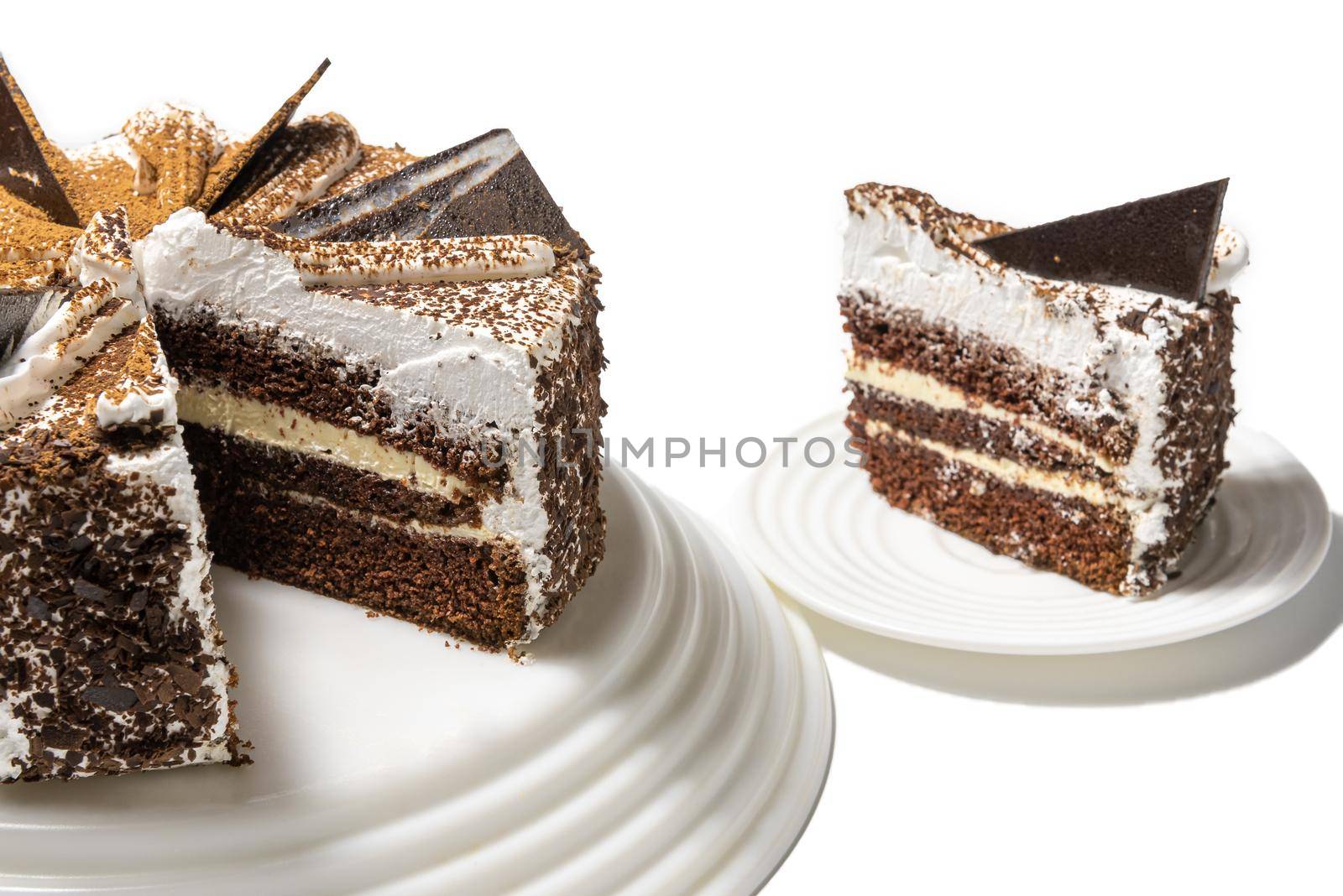 cake with chocolate, sprinkled with chocolate chips, on a tray on a white background with a cut piece.