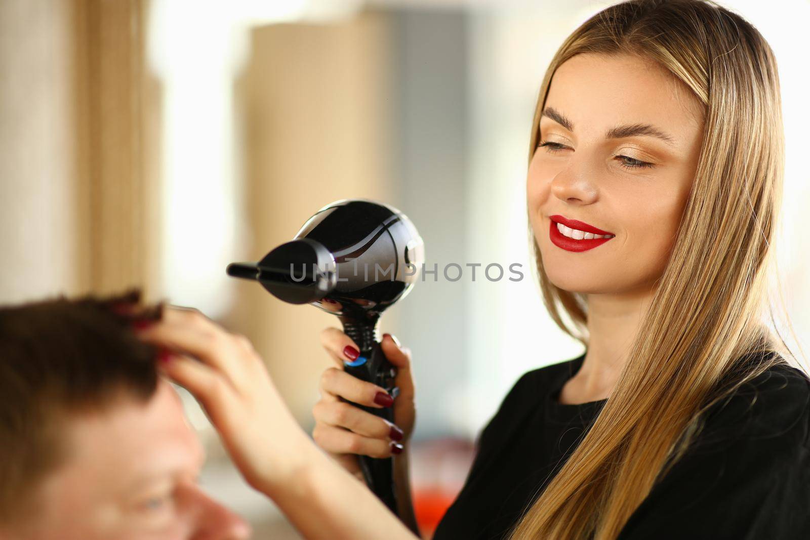 Woman hairdresser doing styling with hairdryer to man by kuprevich