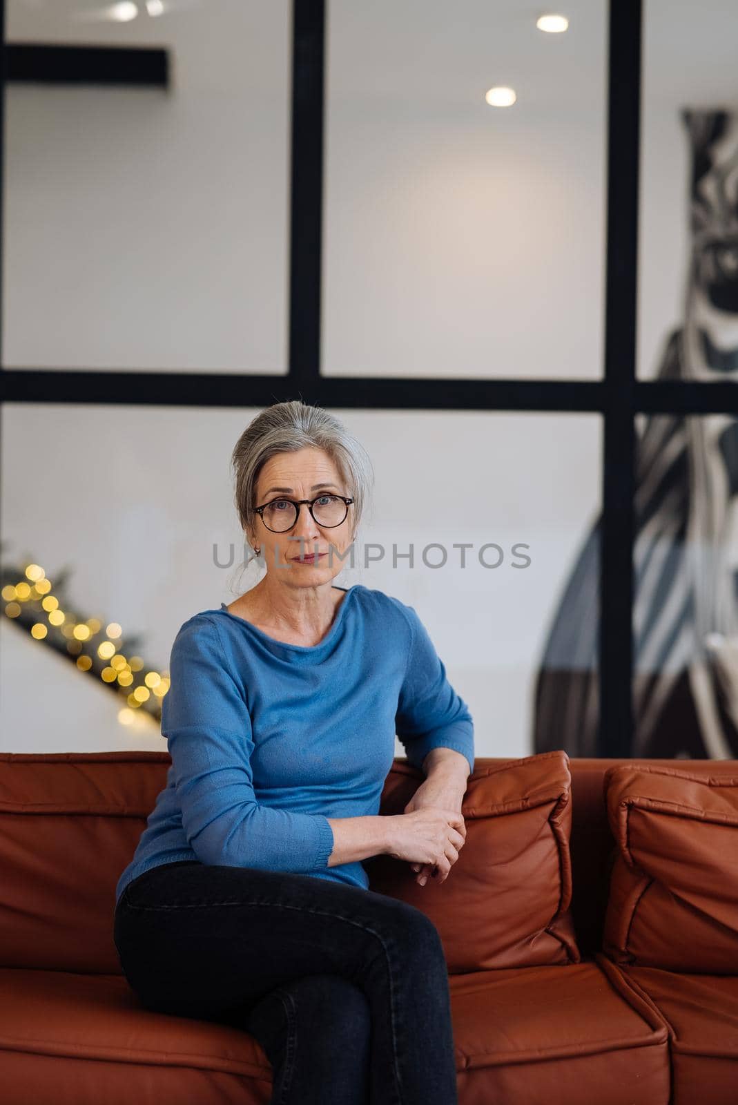 Portrait of a Cheerful Middle Aged Woman Sitting at the Sofa in the Living Room, Looking at Camera.