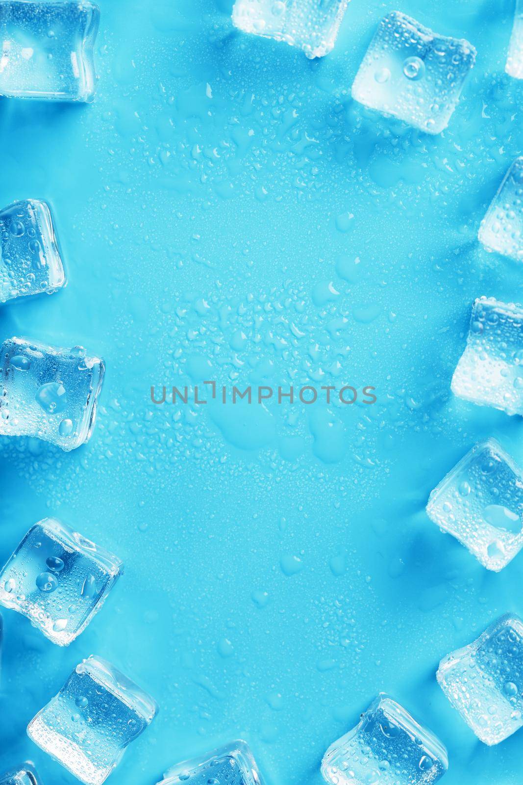 Ice cubes with water drops scattered on a blue background, top view