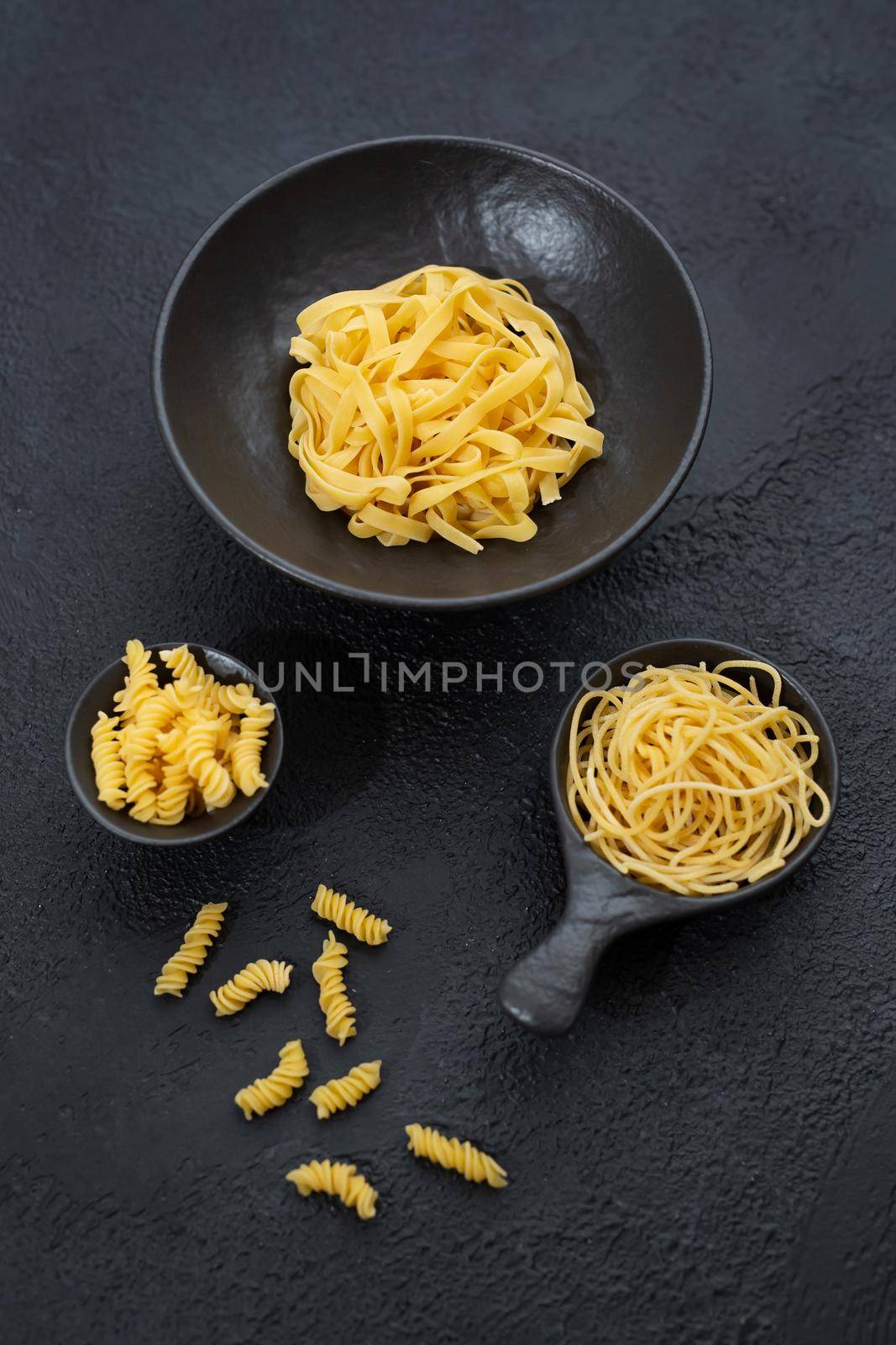 Raw pasta, isolated on a black background, top view.