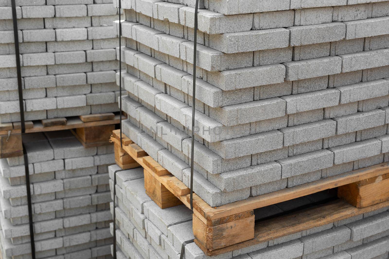 Stack of contemporary stone Paving slabs pavers. Building material on pallet for road paving. Sidewalk tile. Construction site.