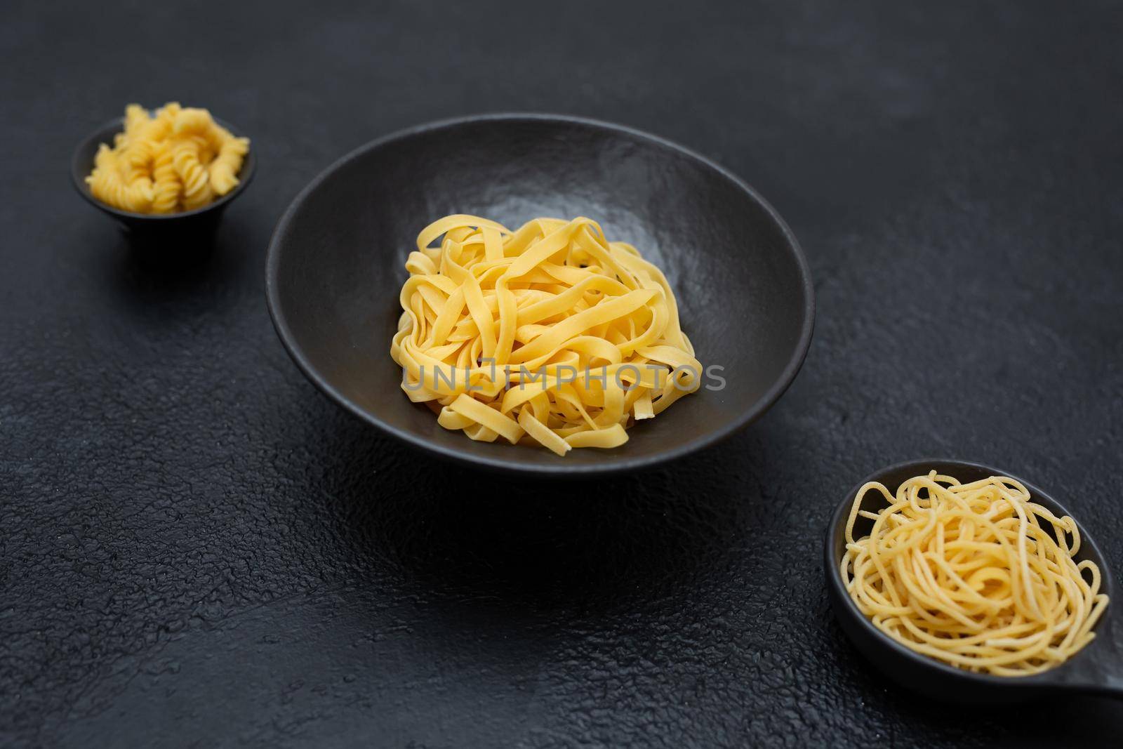 Raw pasta, isolated on a black background, top view by StudioPeace