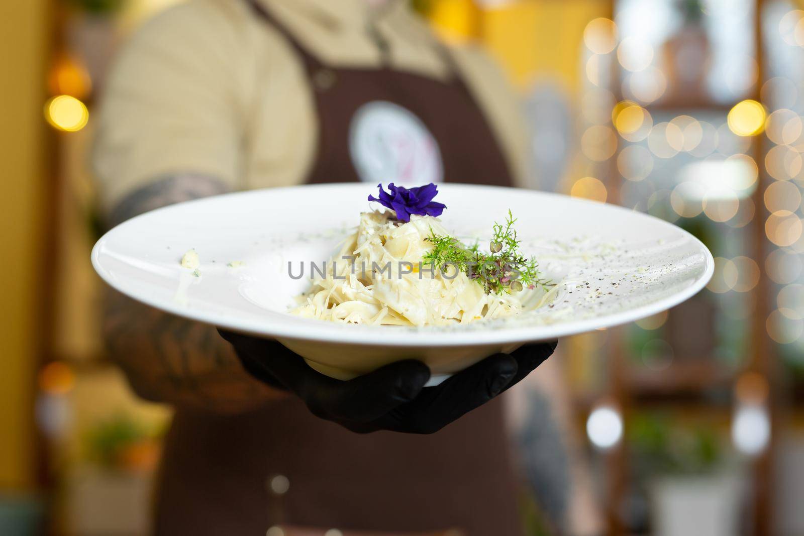 Pasta with cream and parmesan, decorated with edible flowers and microgreen close-up.