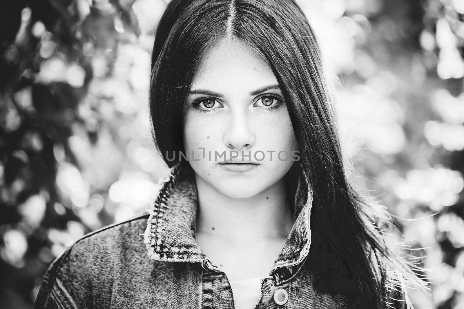 black and white portrait of a teenage girl with long hair on a nature background