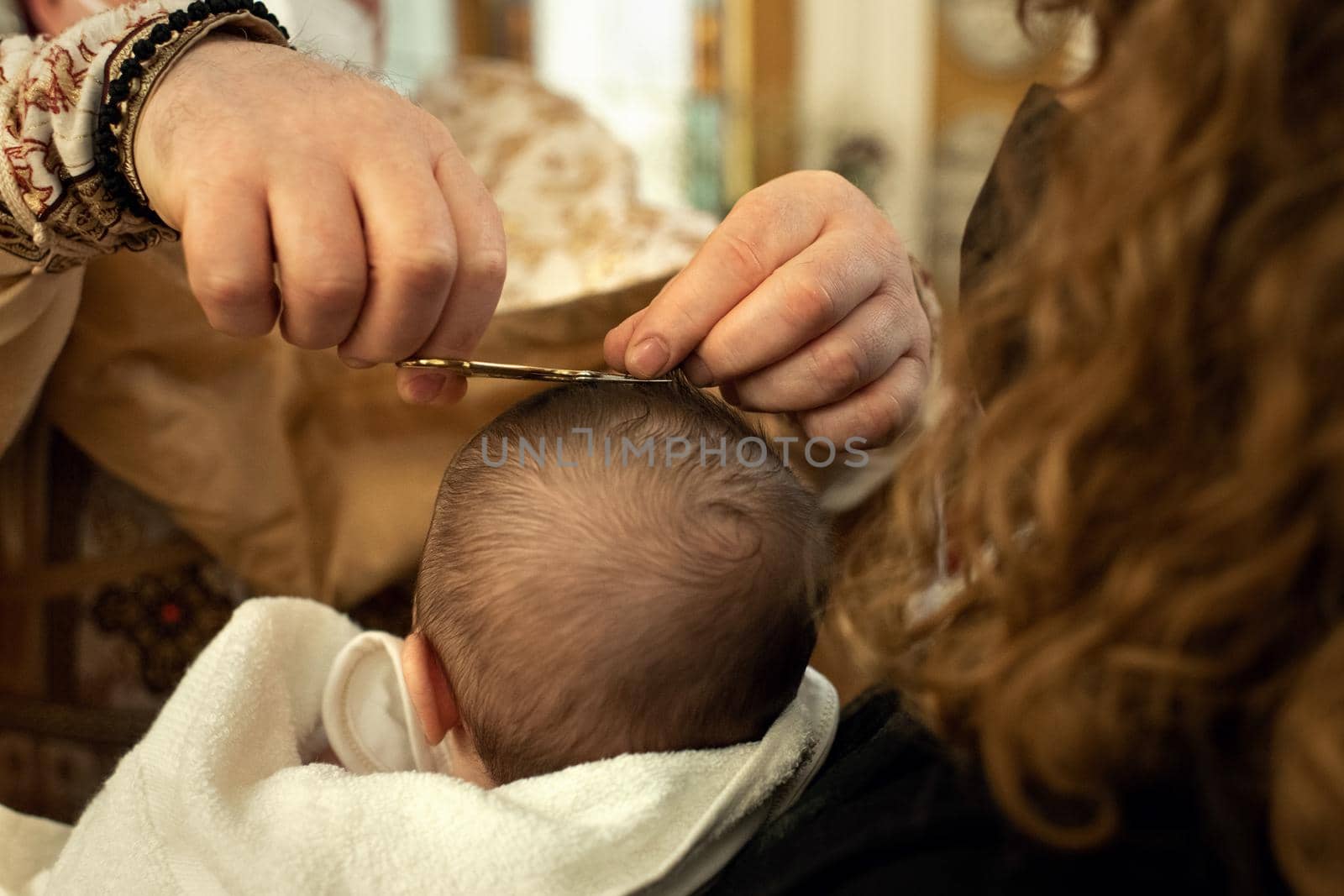 Godmother holds the baby, the priest conducts a ceremony hair cut