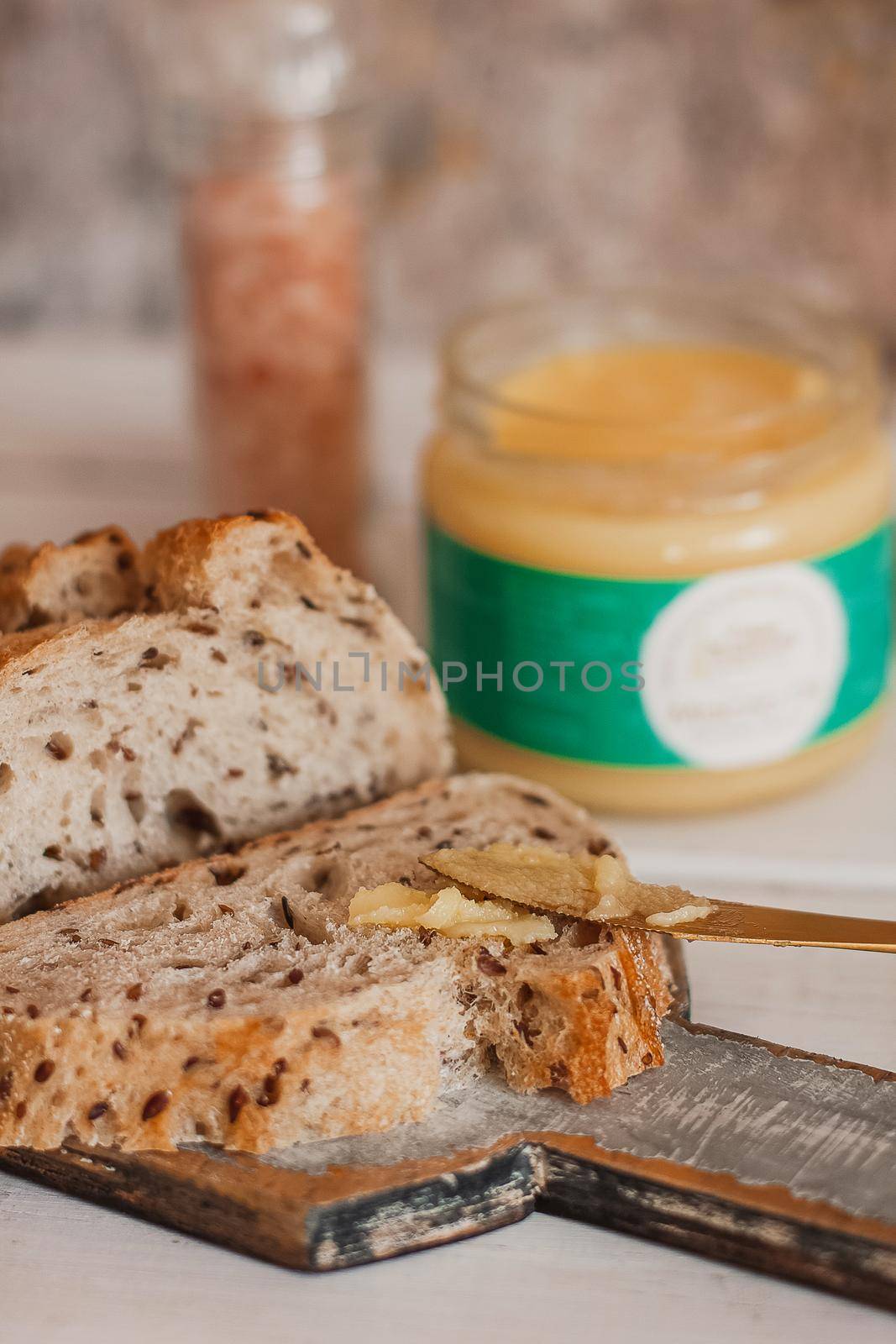 Ghee butter in glass jar and sliced bread on table. Healthy eating, breakfast.