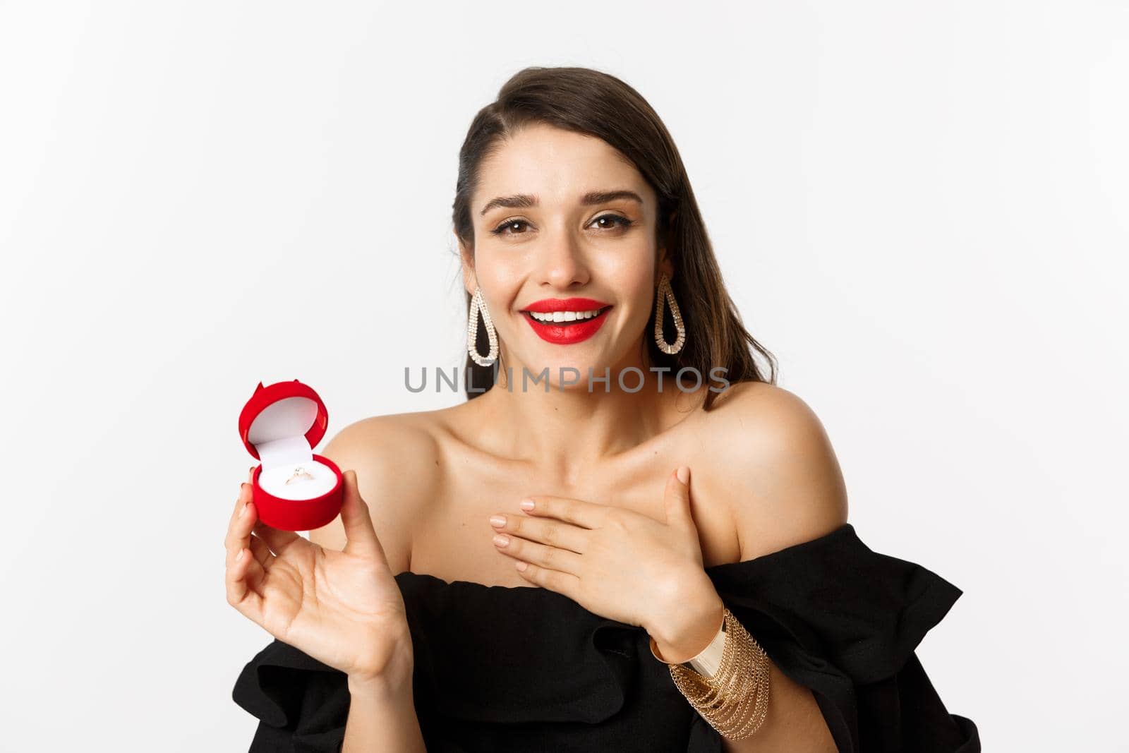 Close-up of happy woman showing her engagement ring, receive marriage proposal, saying yes, standing over white background by Benzoix