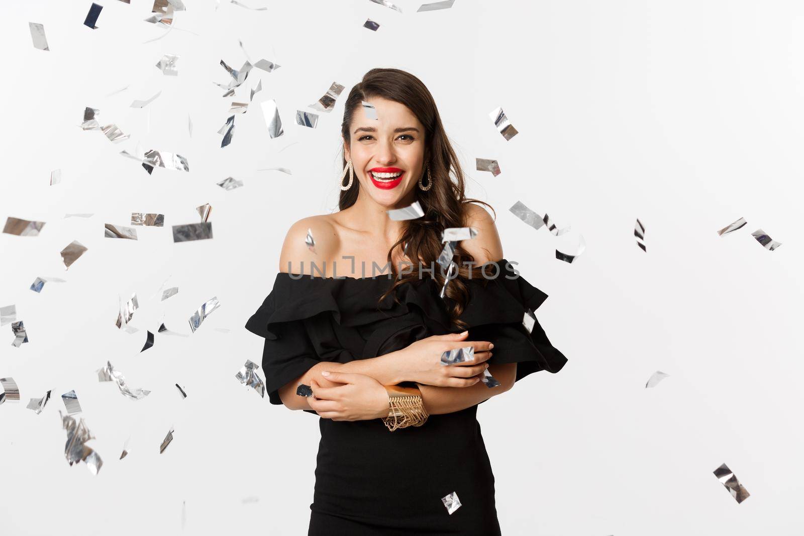 Happy woman celebrating winter holidays, smiling cheerful, partying on New Year with confetti, standing over white background.