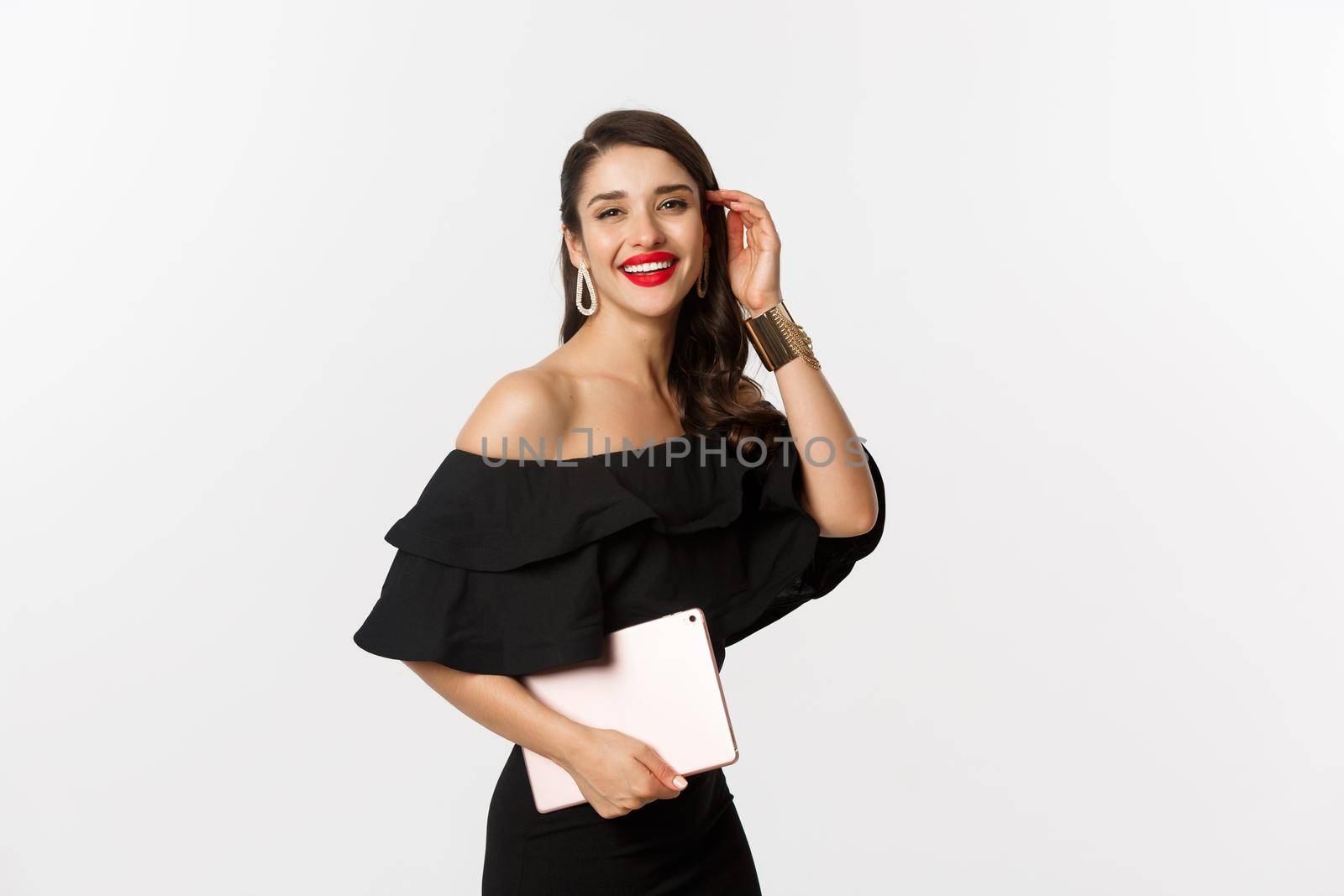 Fashion and shopping concept. Stylish young woman with glamour makeup, wearing black dress, holding digital tablet and smiling, white background by Benzoix