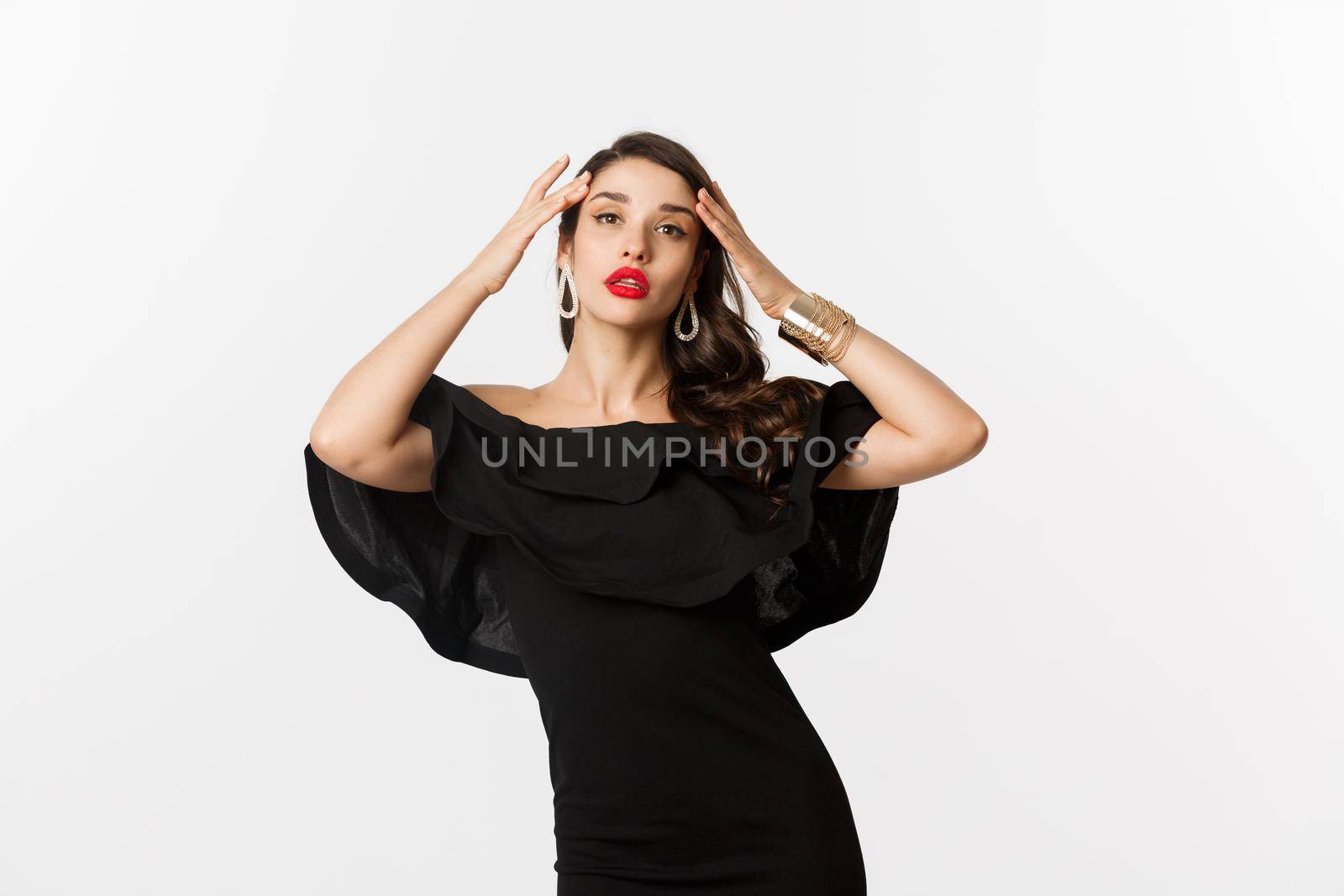 Confident and stylish woman in black elegant dress, looking sassy at camera, standing over white background by Benzoix