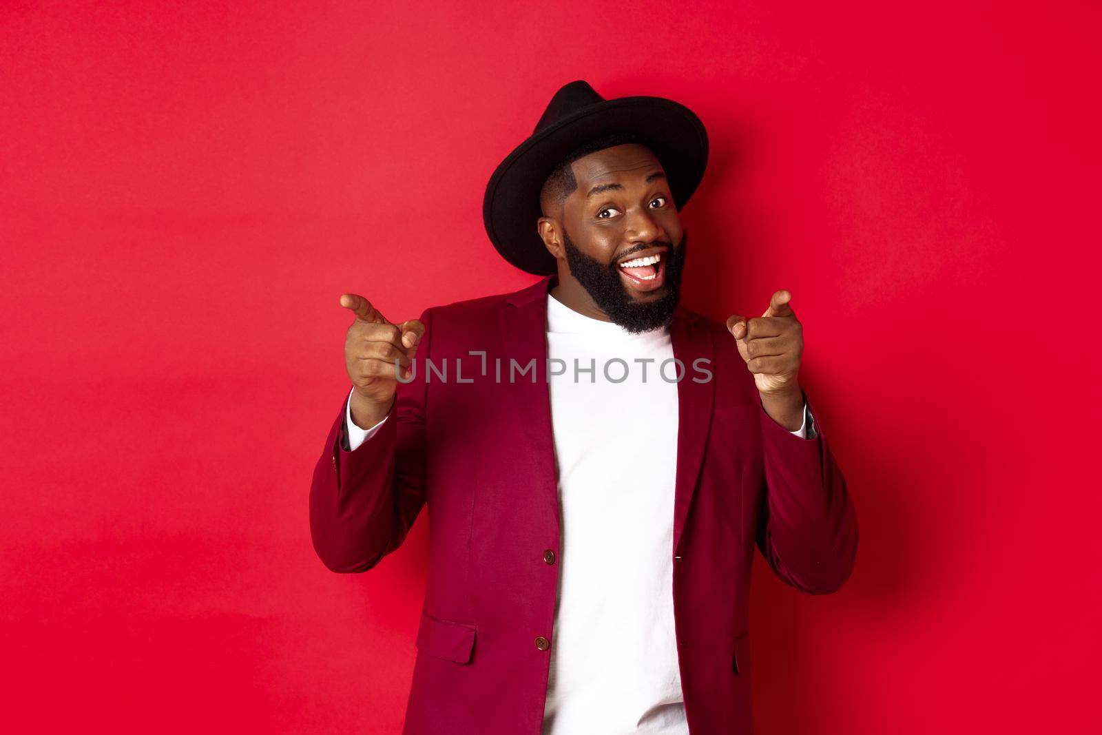 Christmas and people concept. Happy Black man celebrating New Year and dancing, wearing party outfit, red background by Benzoix