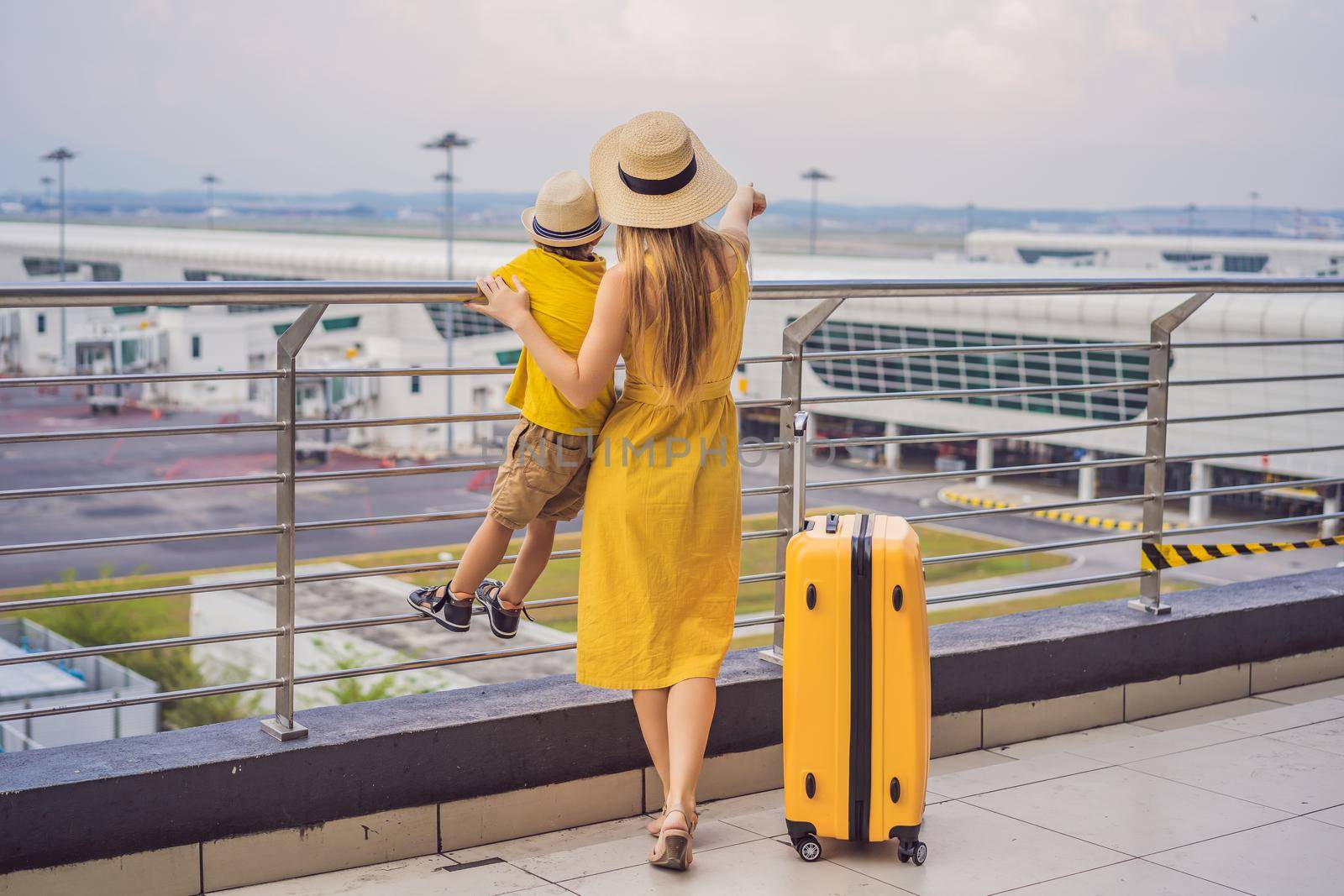 Family at airport before flight. Mother and son waiting to board at departure gate of modern international terminal. Traveling and flying with children. Mom with kid boarding airplane. yellow family look by galitskaya