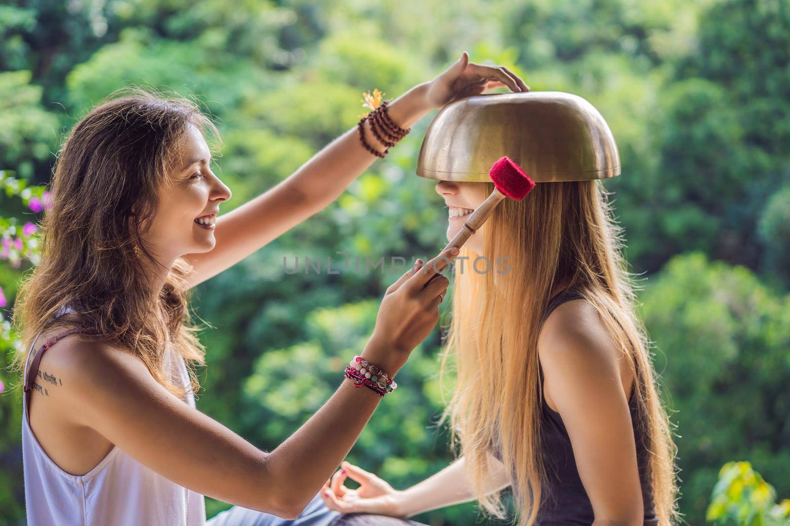 Nepal Buddha copper singing bowl at spa salon. Young beautiful woman doing massage therapy singing bowls in the Spa against a waterfall. Sound therapy, recreation, meditation, healthy lifestyle and body care concept.