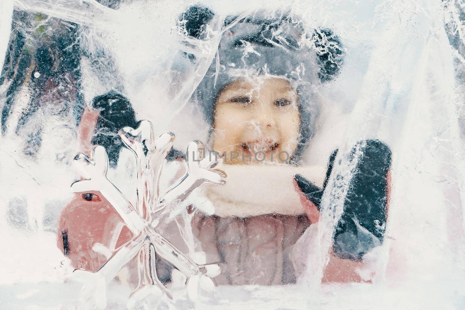 portrait of a little smiling girl looking through an ice fortress by Lena_Ogurtsova