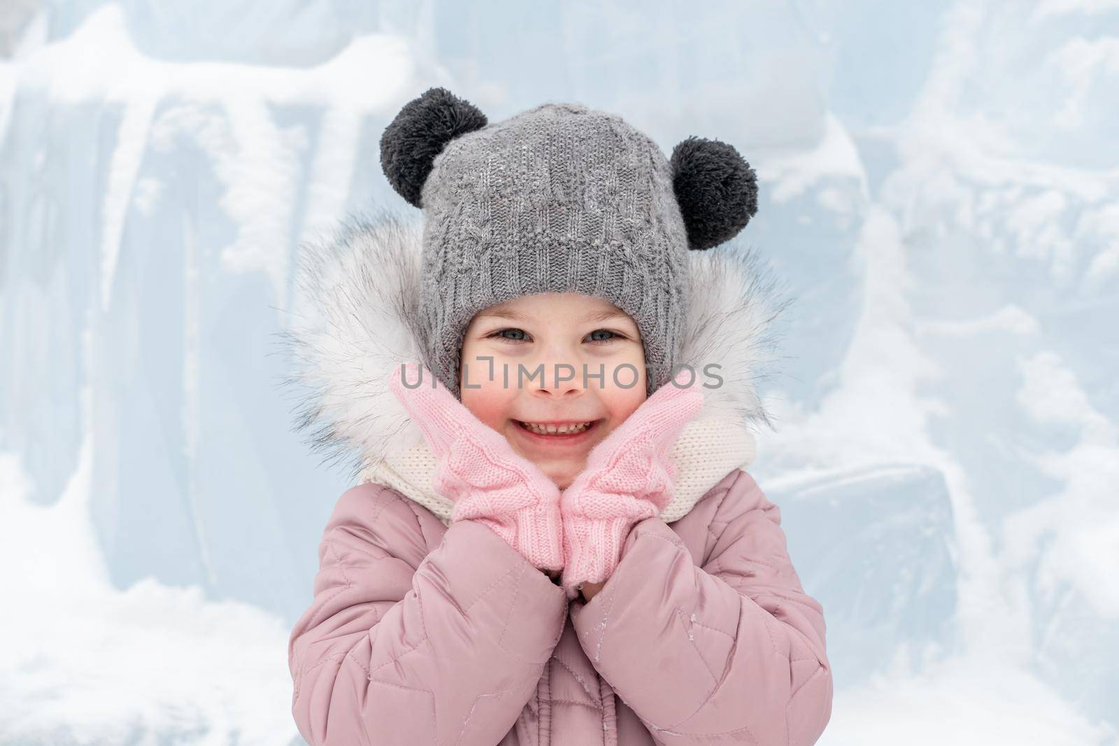 playful child girl is happy near the ice palace on a winter day