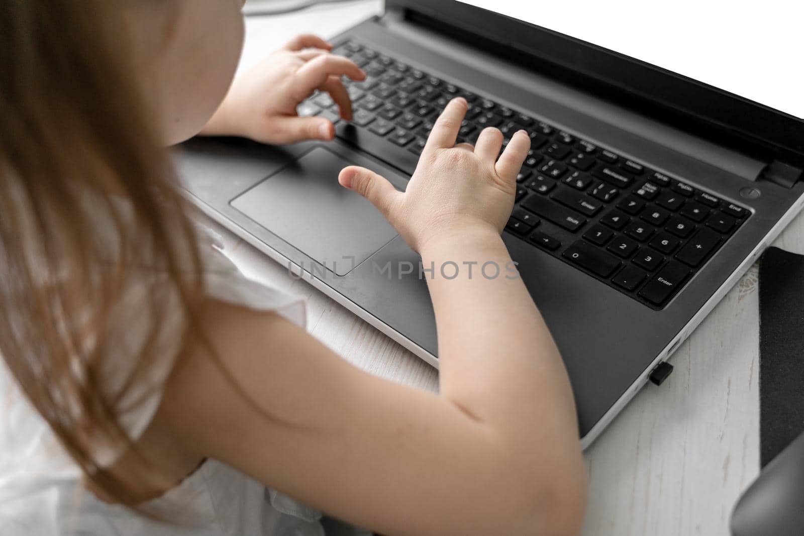 cute little caucasian girl studying online at home. hands on the keyboard close-up